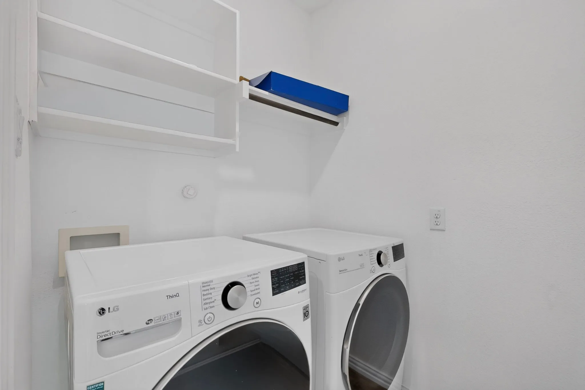White painted walls with built-in shelving, a clothes hanging rod, and a utility outlet