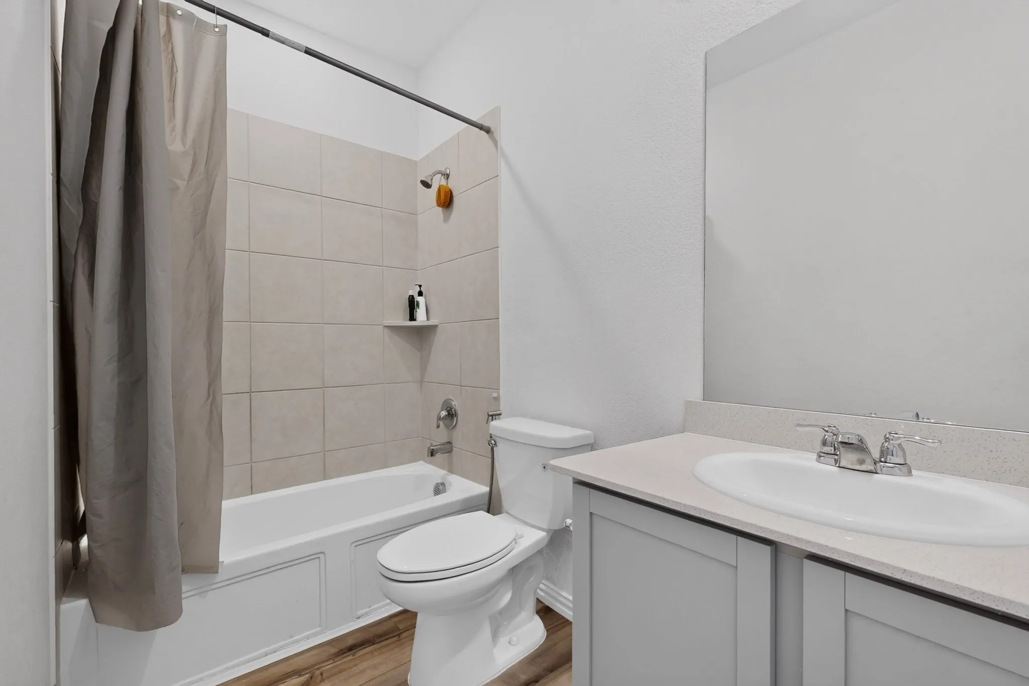 Bathroom featuring a tub/shower combination with tile surround, built-in shelving, a single vanity with an integrated sink, and wood-finish flooring