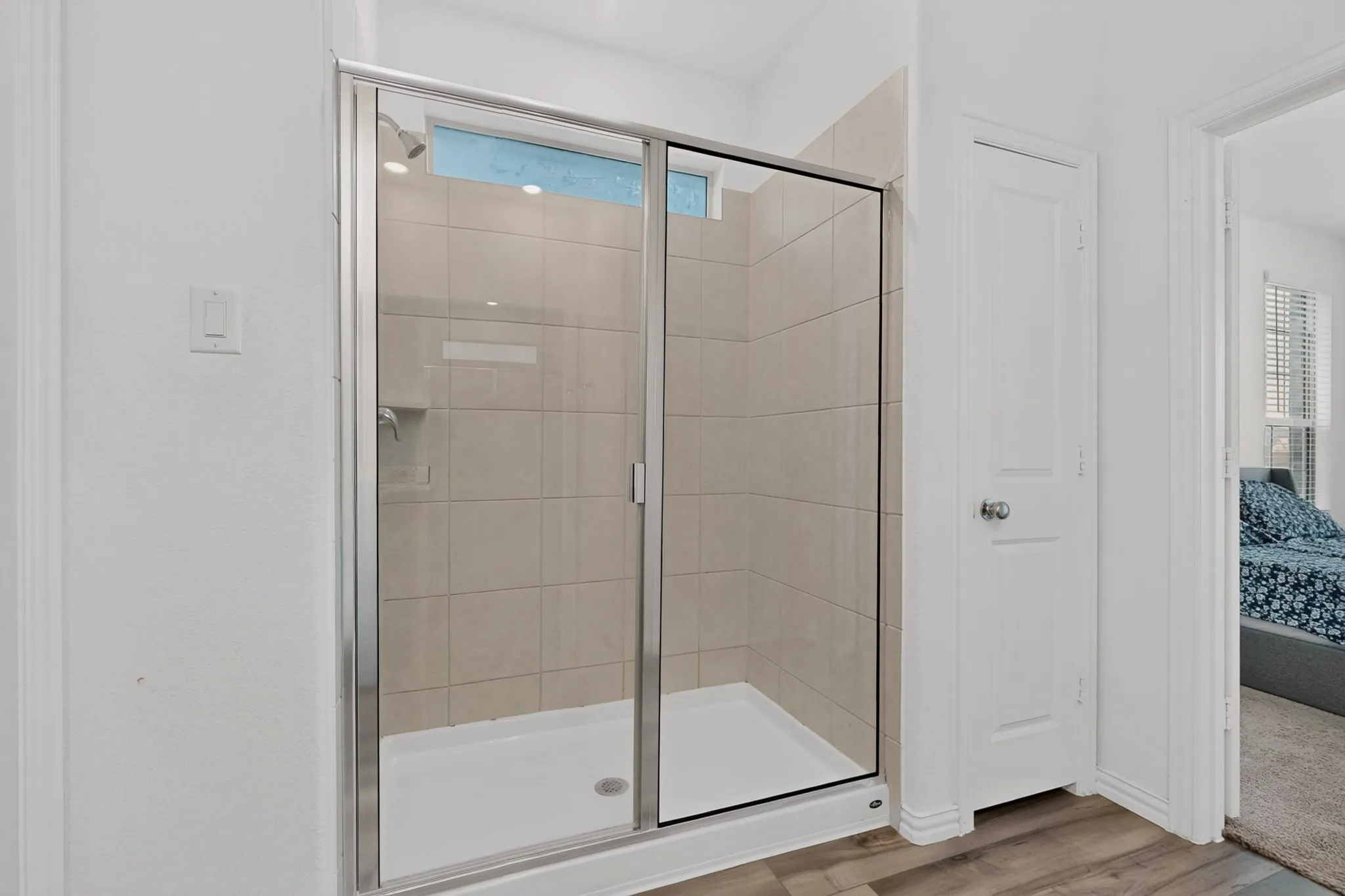 Tiled shower enclosure with a glass sliding door, integrated shower niche, and a transom window
