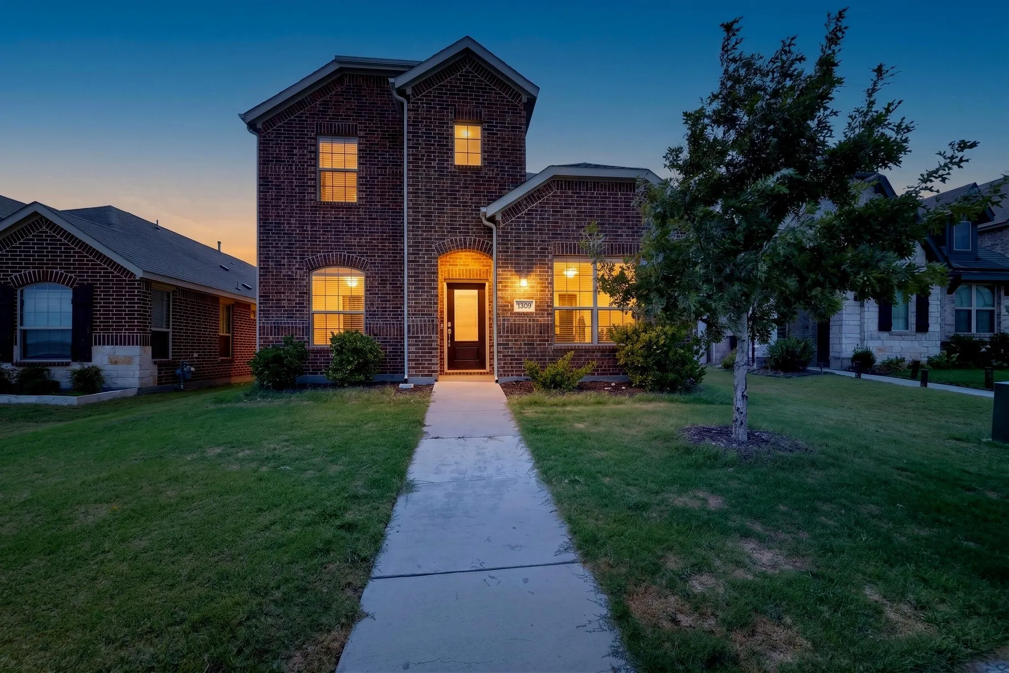 Brick exterior with a prominent arched entry, transom window, and a concrete pathway leading to the front door