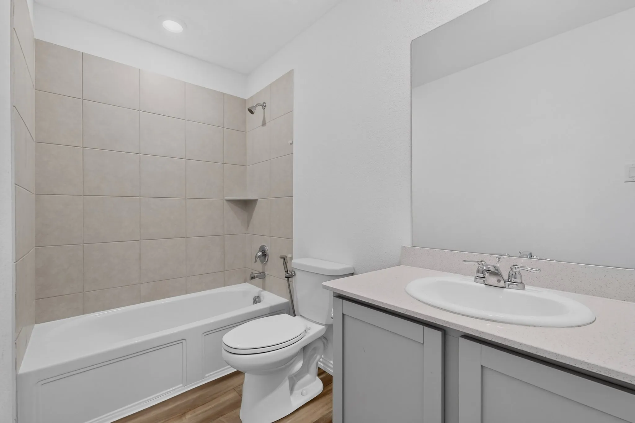 Full bathroom featuring a tub-shower combination with tiled surround, a built-in shower niche, and wood-finish flooring