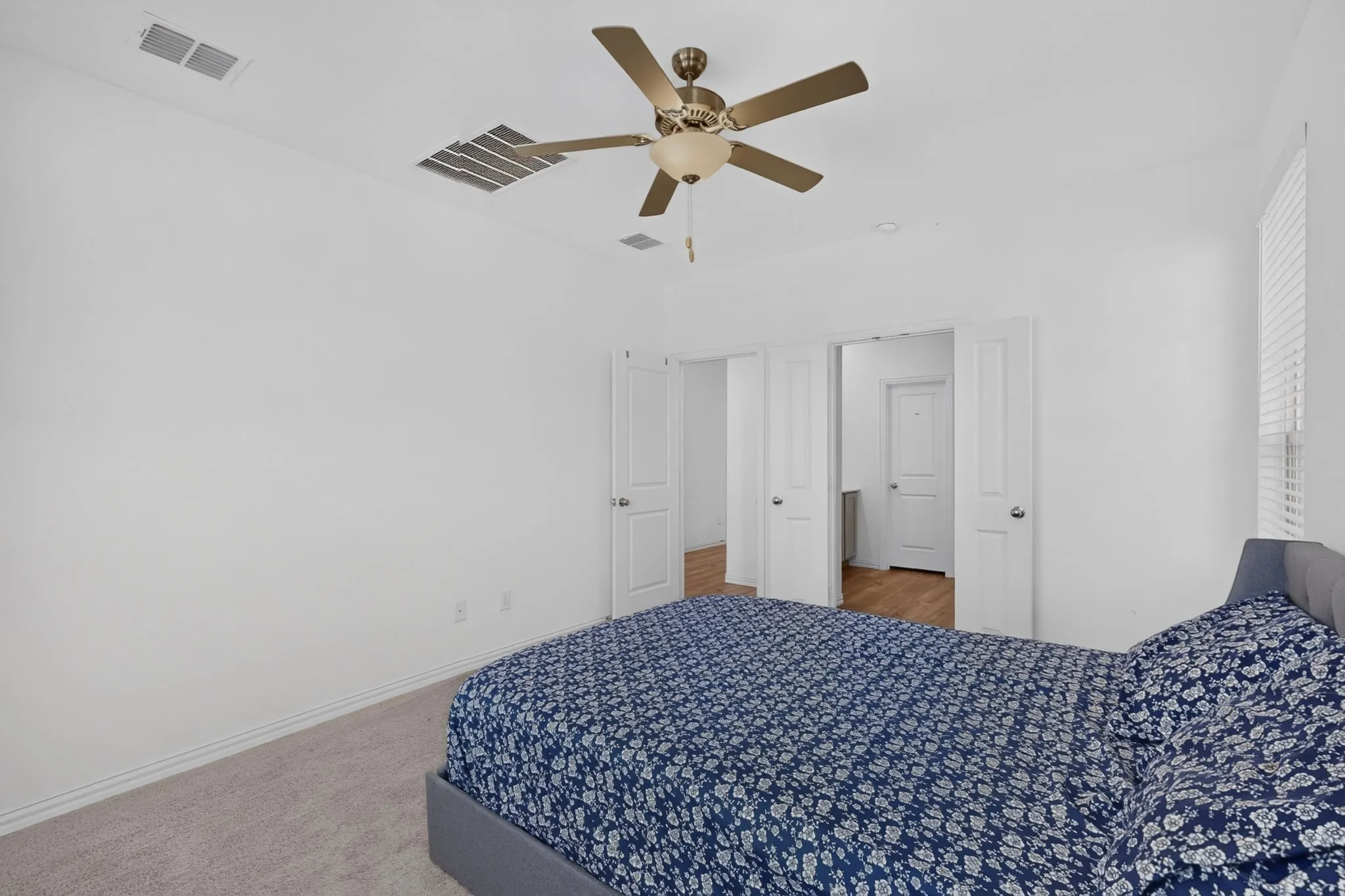 White walls with carpet flooring, complemented by a ceiling fan with integrated lighting