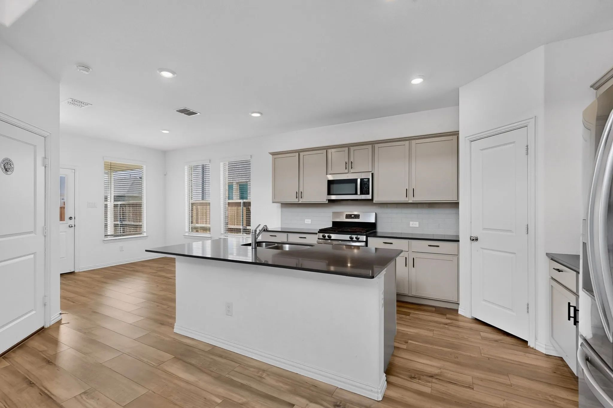 Kitchen featuring a central island with an undermount sink, stainless steel appliances, and wood-finish flooring