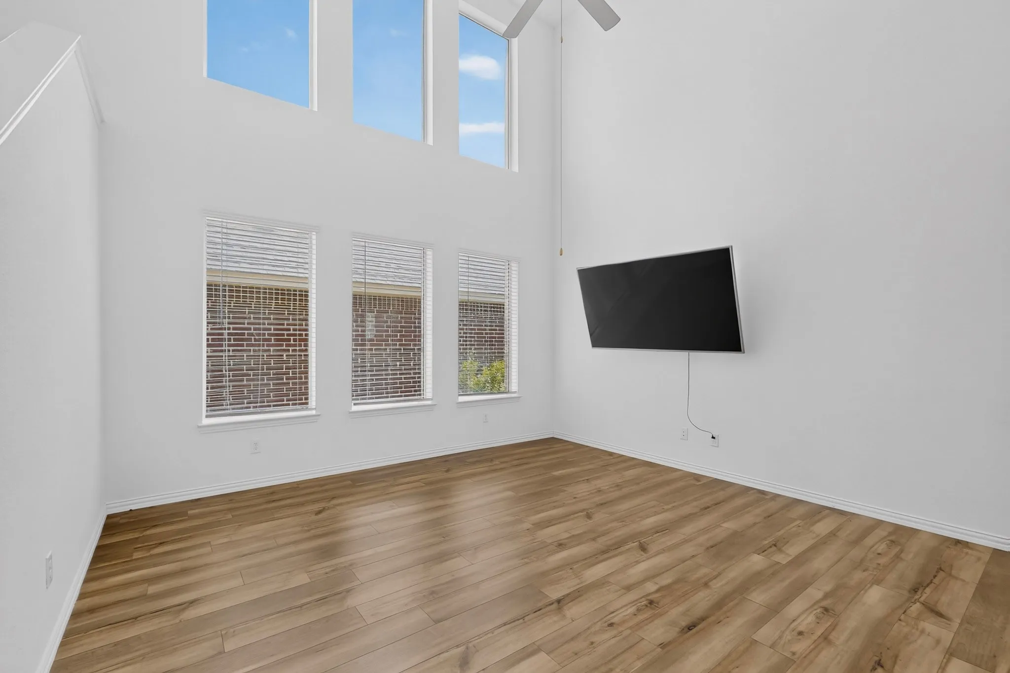 High ceilings with upper transom windows, wood-finish flooring, and a ceiling fan