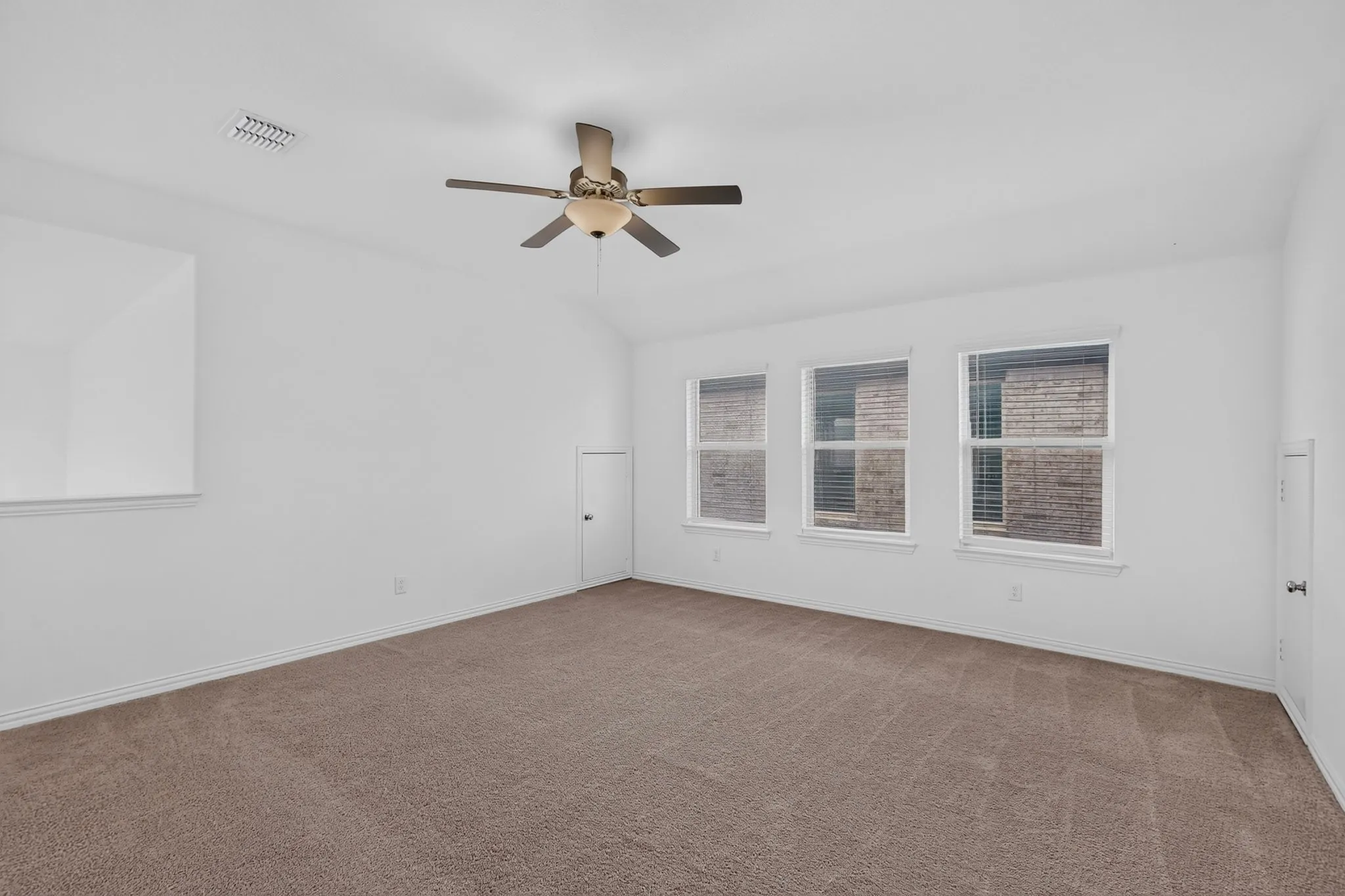 Spacious room featuring vaulted ceilings, a ceiling fan with integrated lighting, and carpet flooring