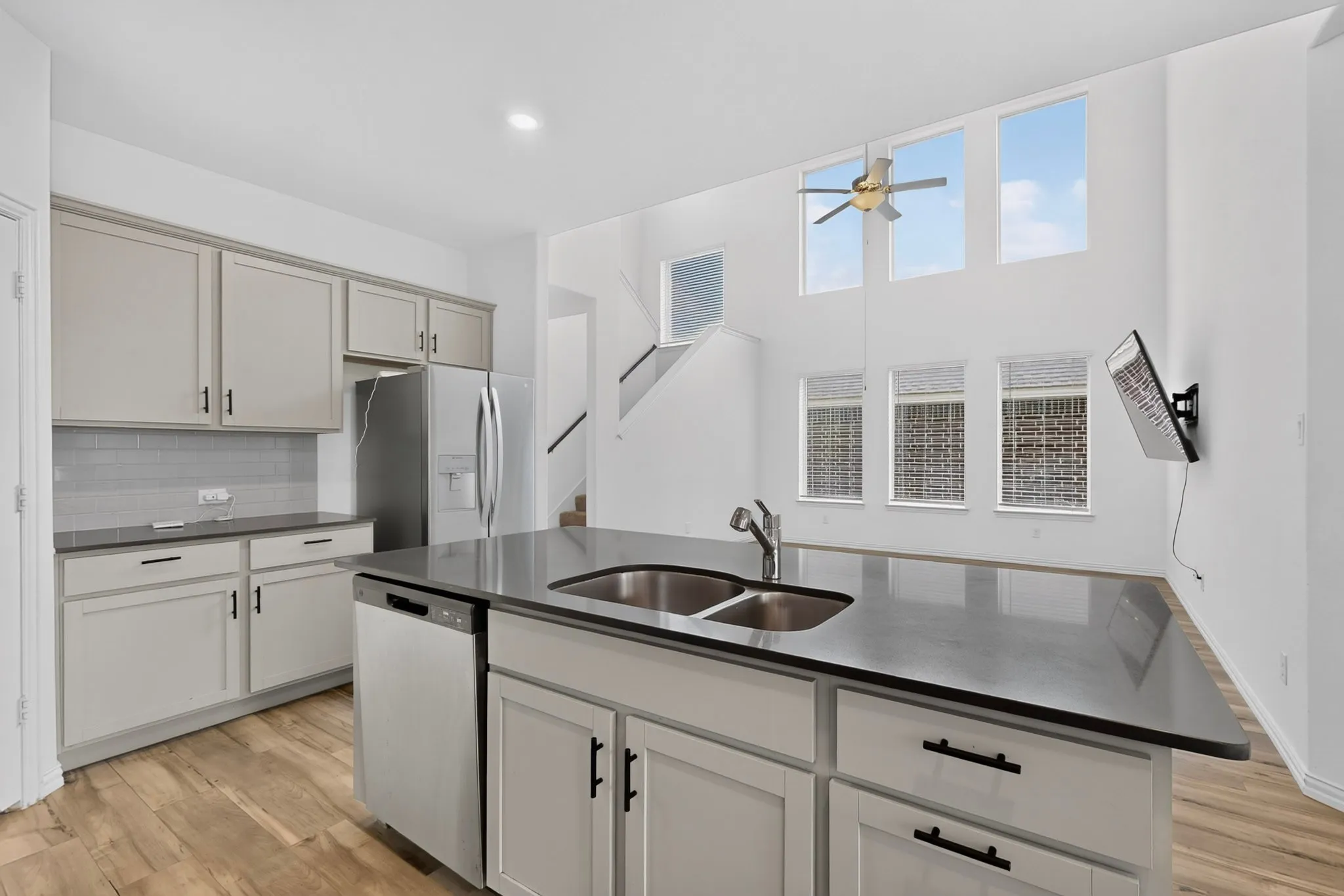 Kitchen island with a double basin sink, stainless steel dishwasher, and dark countertops