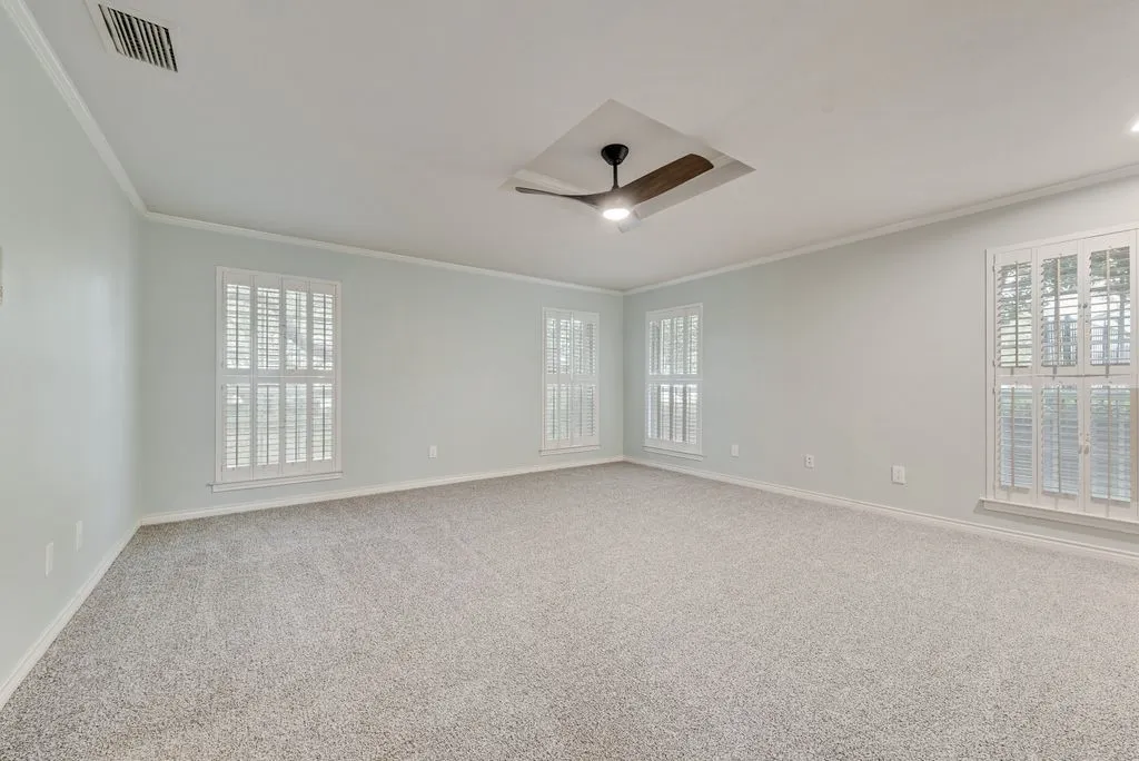 Spacious room featuring light-colored walls, crown molding, and plush carpeting