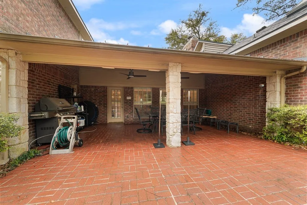 Covered patio featuring a brick paver floor, brick exterior walls, and stone-clad support columns