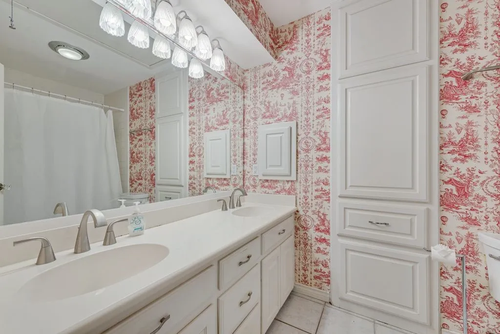 Dual vanity with integrated sinks, brushed nickel fixtures, and a multi-bulb lighting fixture