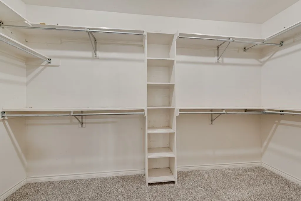 Custom closet system featuring built-in shelving, hanging rods, and light-tone carpeting