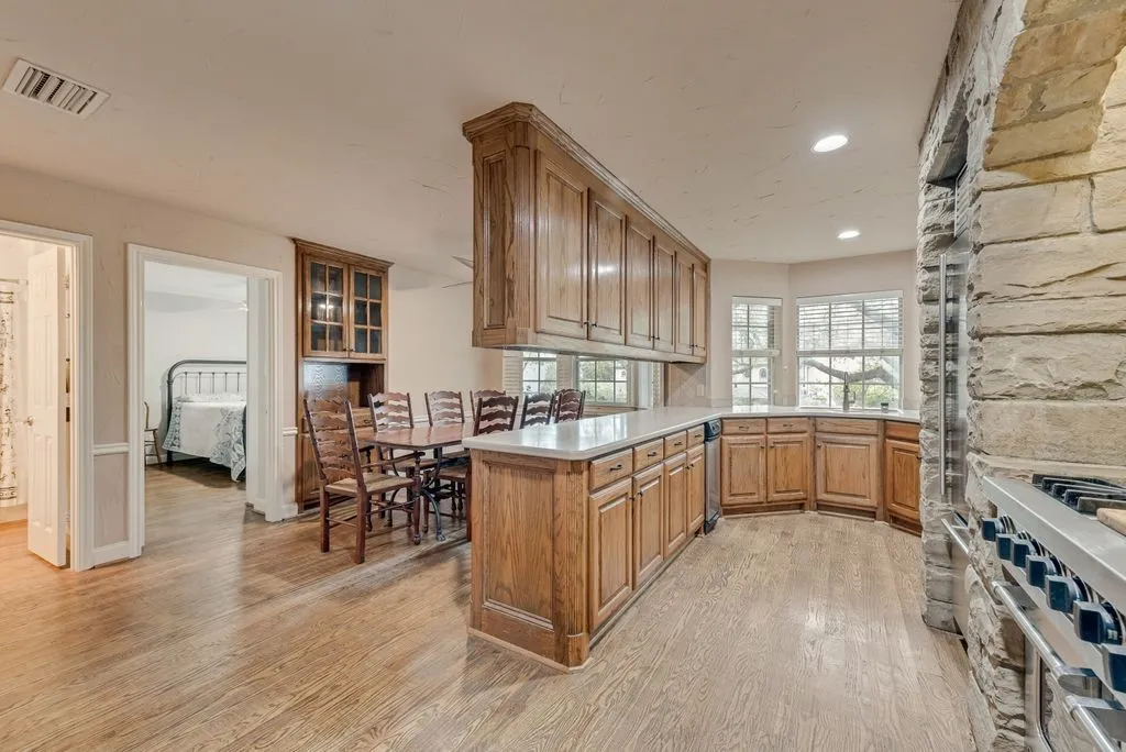 Kitchen featuring wood-finish flooring, custom wood cabinetry, and stone architectural details