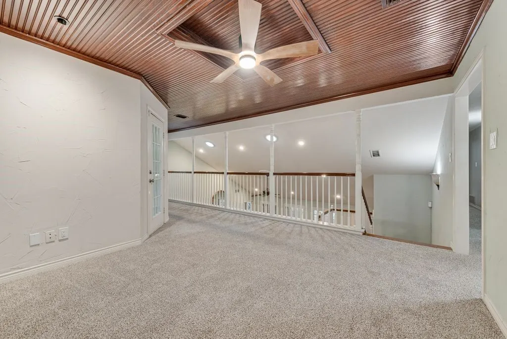 Loft area with wood-paneled ceiling, ceiling fan, carpet flooring, and white railing overlooking lower level