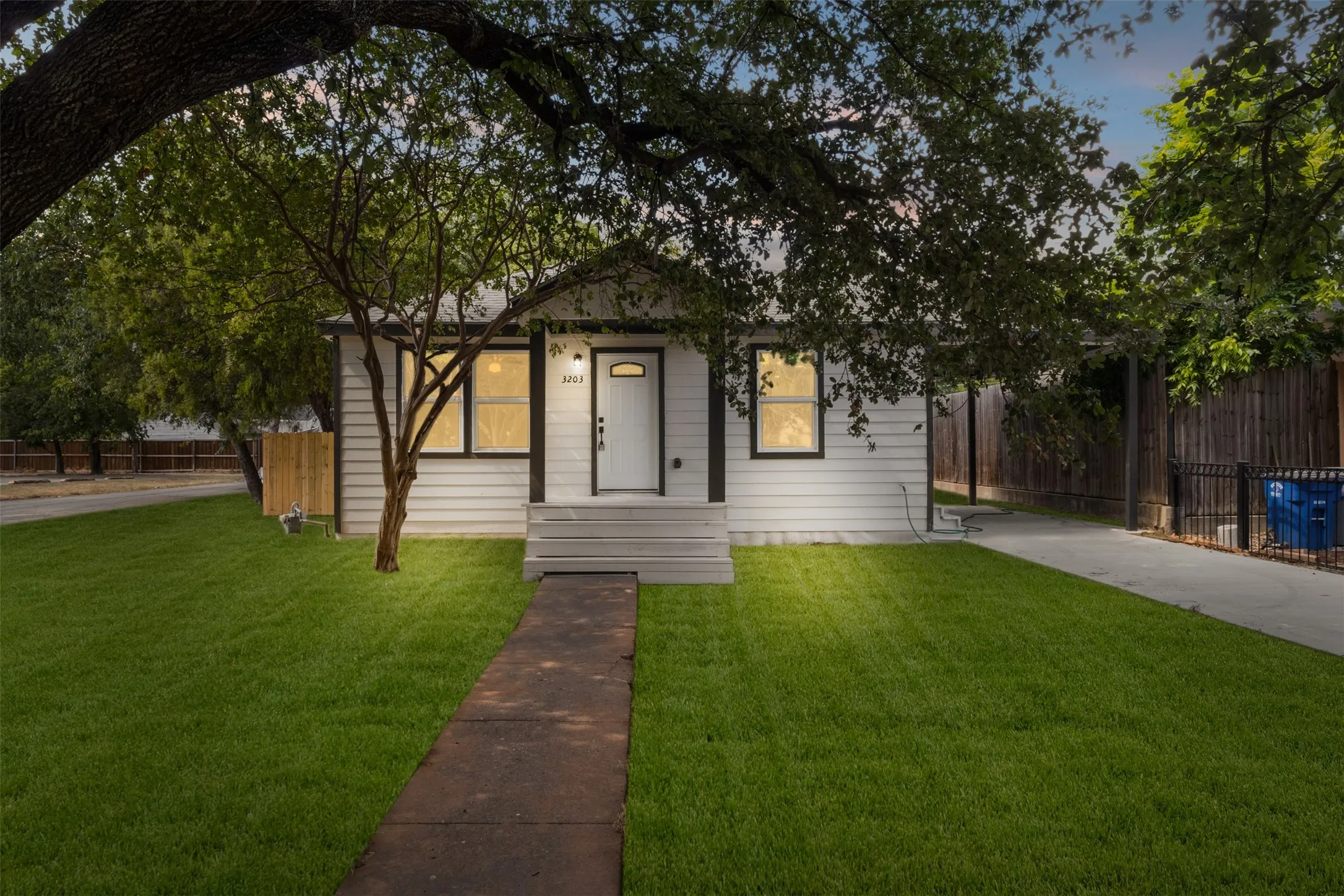 White siding exterior with black trim, front entry porch, concrete pathway, and a well-maintained lawn