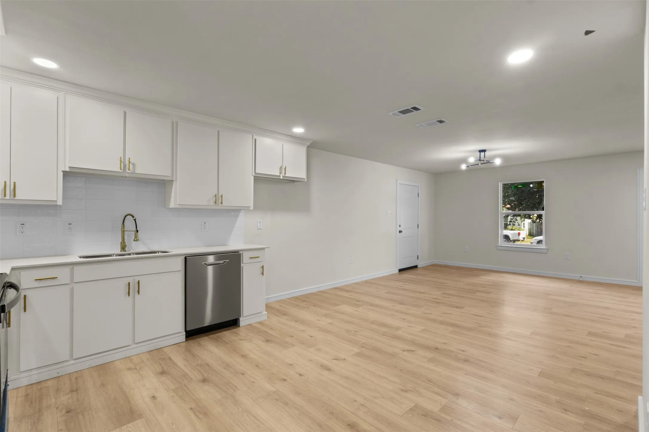 Open-concept living area with wood-finish flooring, recessed lighting, and a modern ceiling fixture