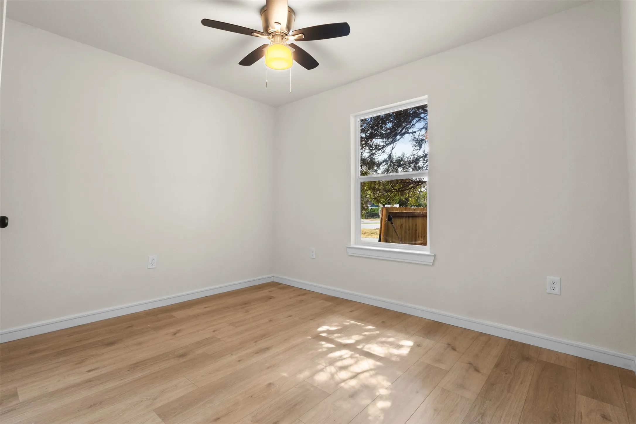 Light-toned wood-finish flooring, white walls, and a ceiling fan with integrated lighting