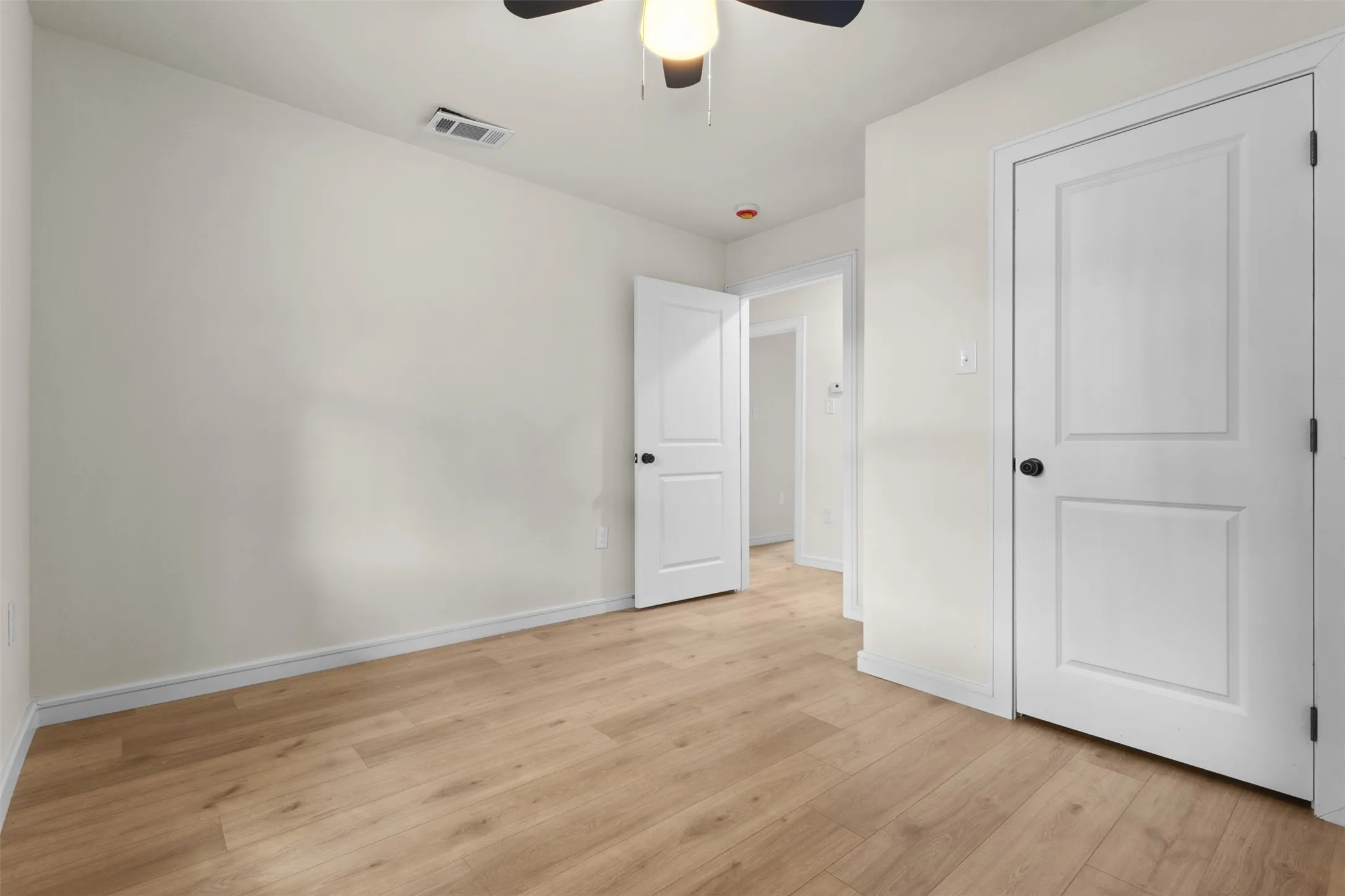 Light wood-finish flooring with white baseboards and neutral wall tones