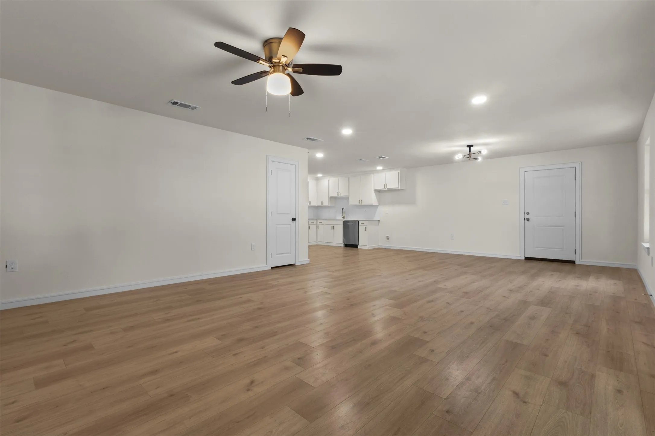 Wood-finish flooring throughout, bright recessed lighting, ceiling fan, and white painted walls