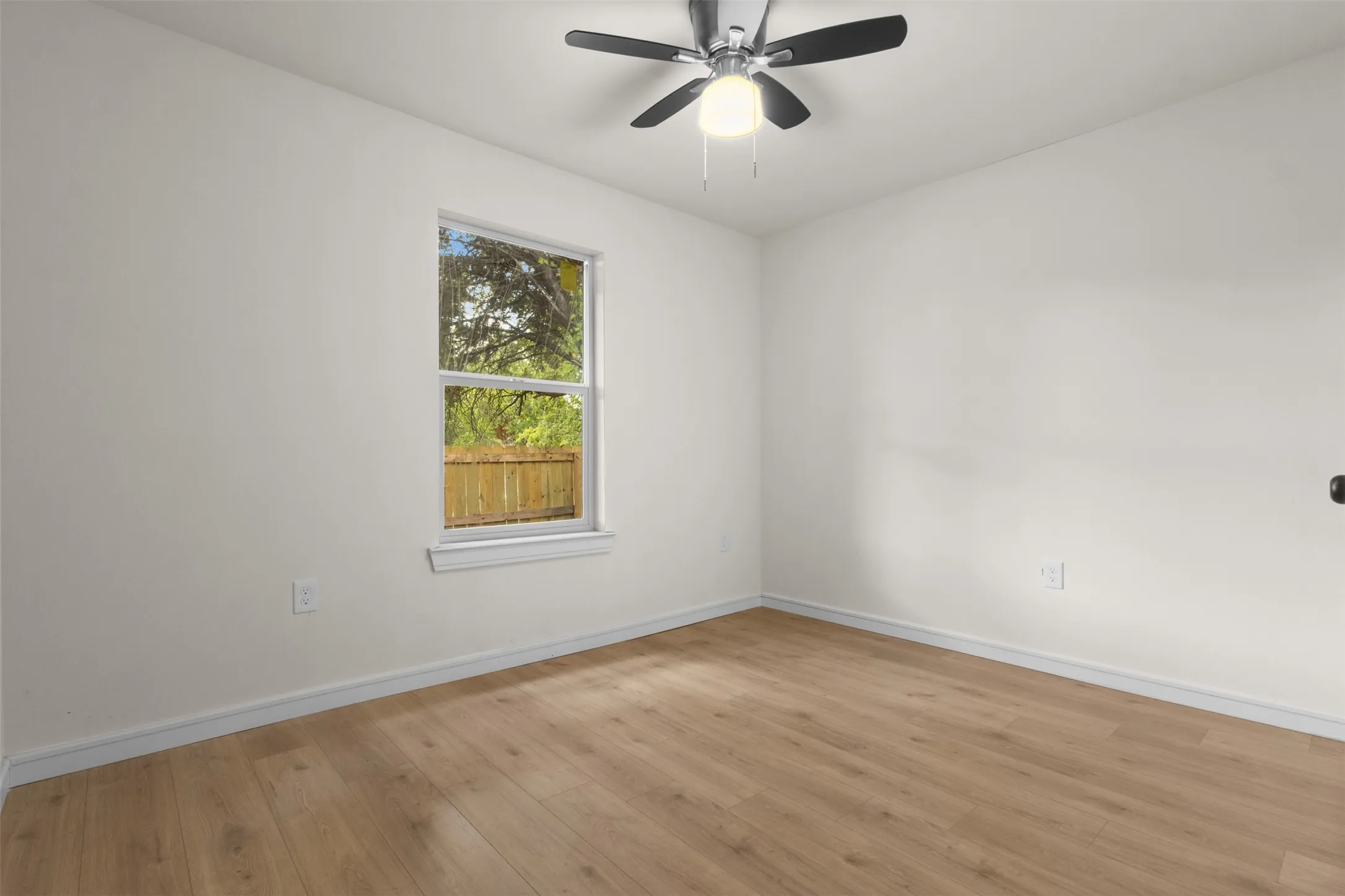 Recessed ceiling fan with integrated lighting, wood-finish flooring, white walls, and a window with white trim