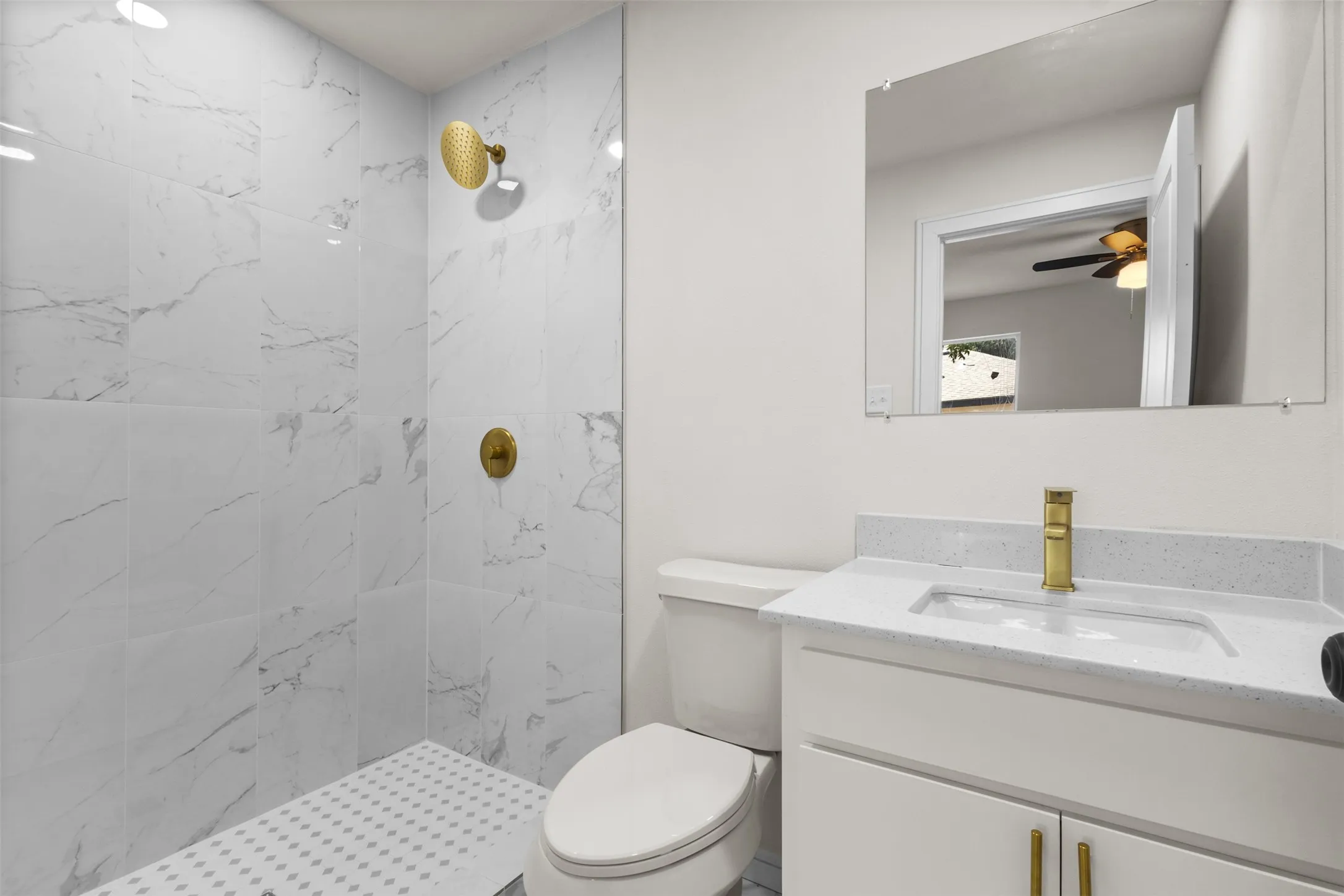 Walk-in shower with tiled walls and floor, featuring gold-toned fixtures
