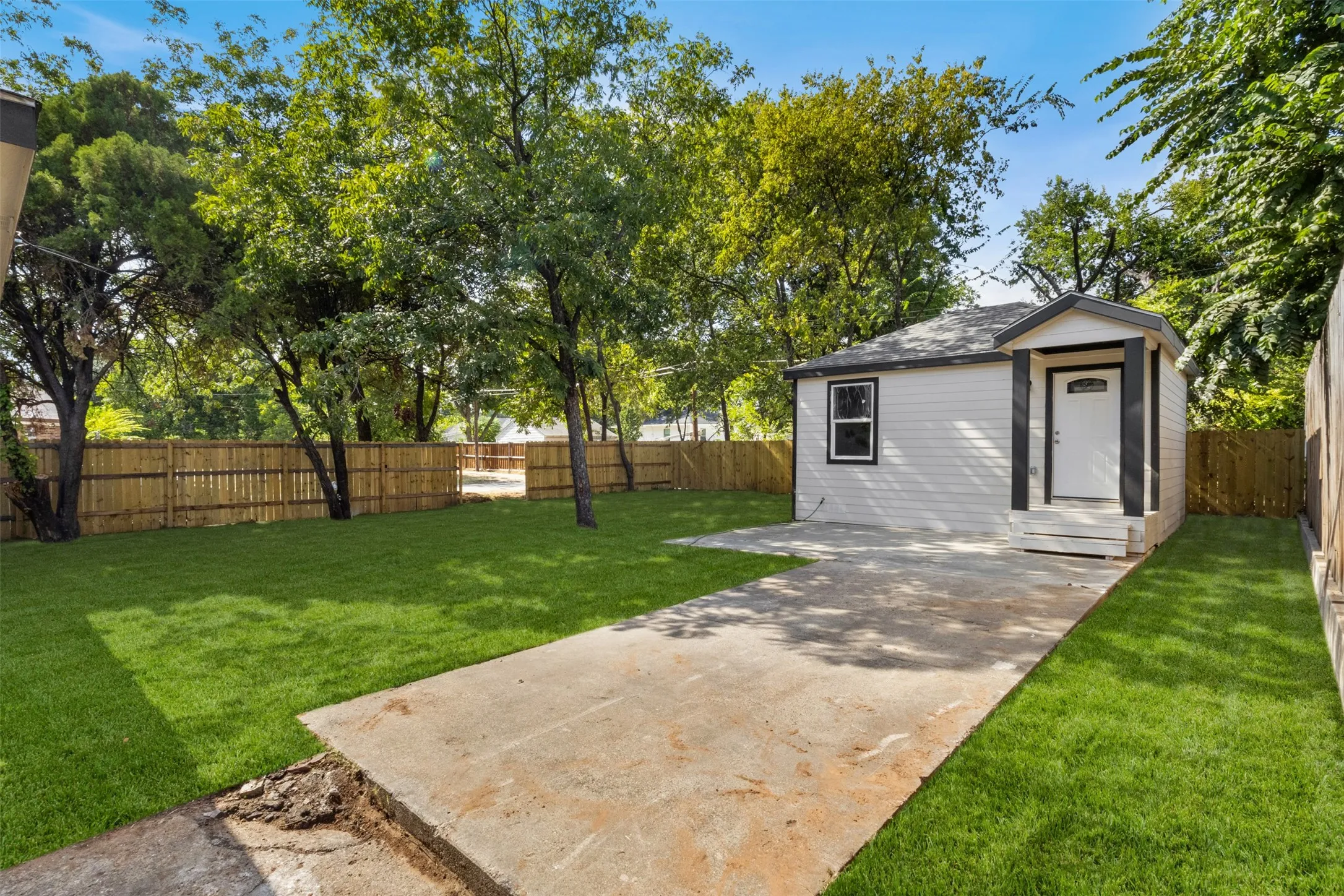 White exterior siding with dark trim accents, covered front porch, and a concrete driveway