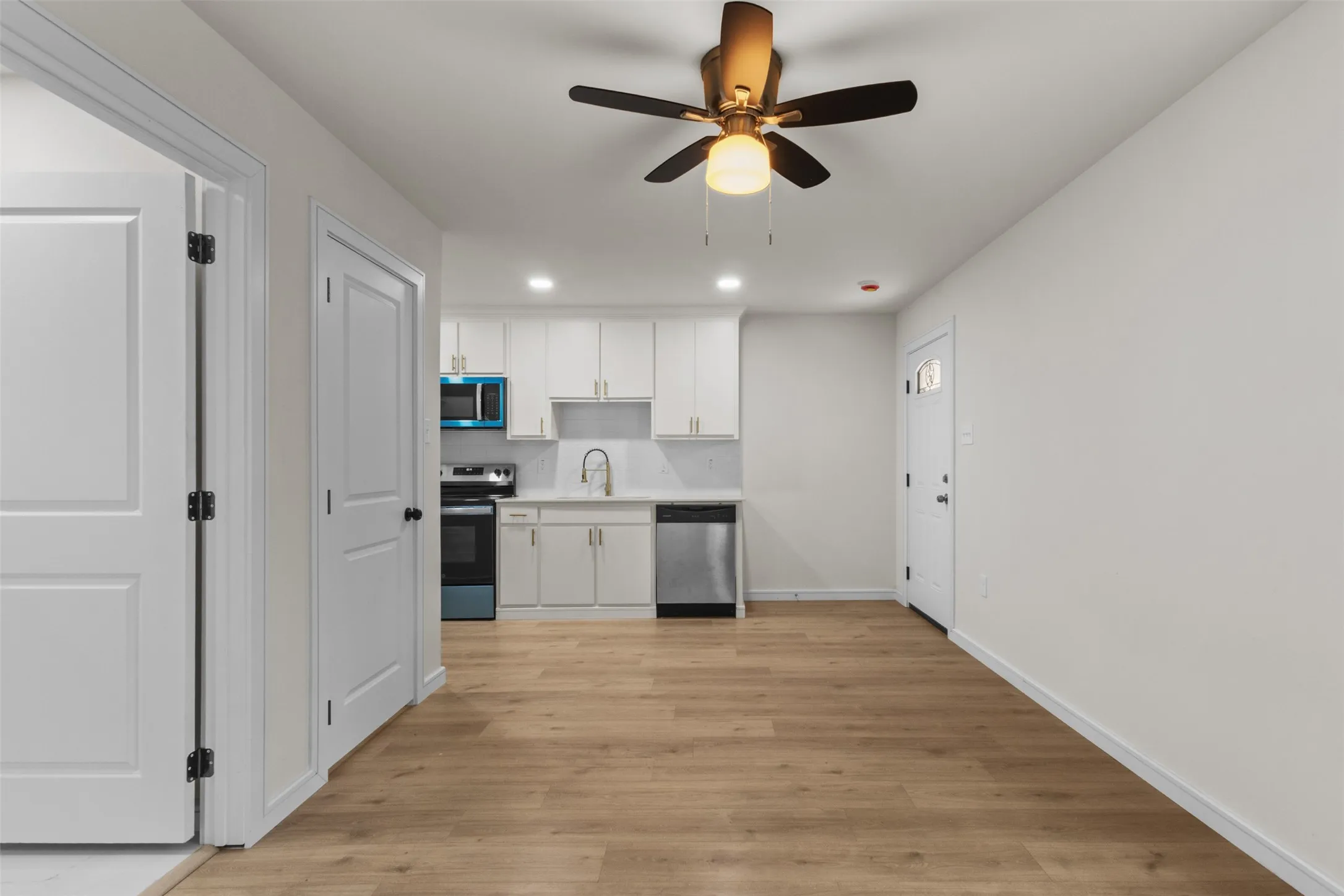 Open-concept living space with wood-finish flooring, a contemporary ceiling fan, and recessed lighting