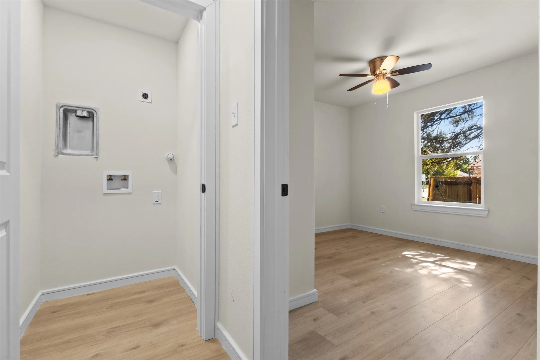 Wood-finish flooring throughout, bright white walls, and a ceiling fan with integrated lighting