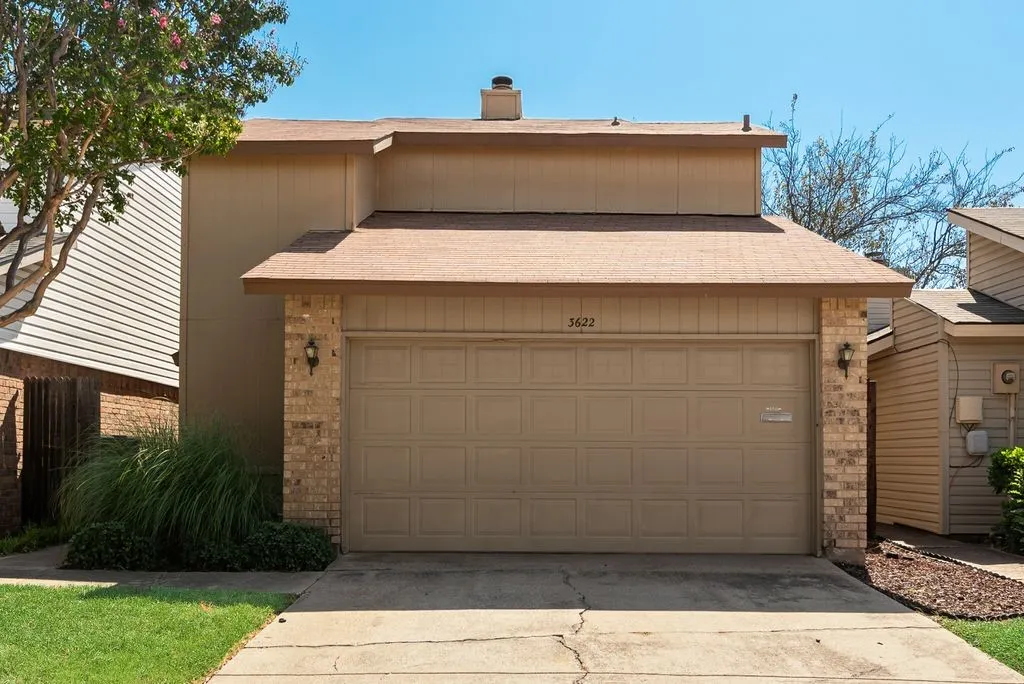 Two-story residence featuring a two-car garage, brick accents, and a shingled roof