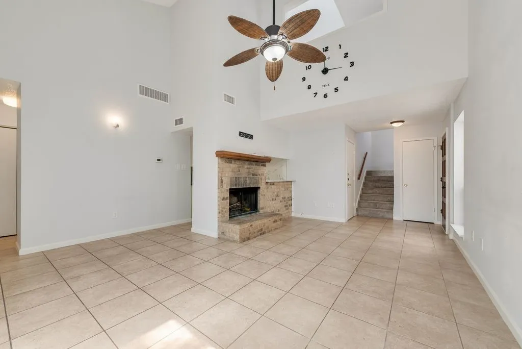 Vaulted ceilings, tile flooring, and a floor-to-ceiling brick-surround fireplace
