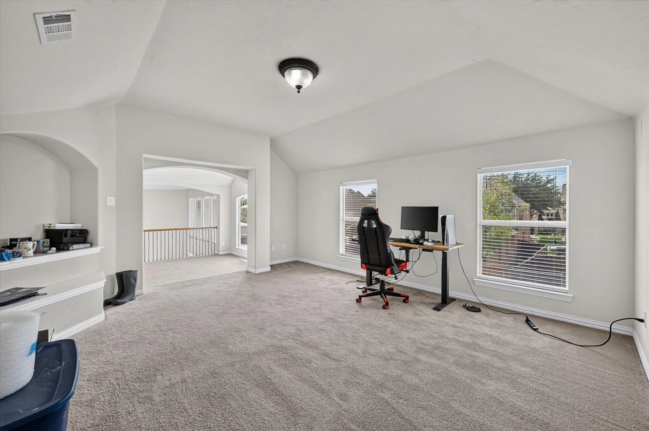 Carpeted room featuring multiple windows with blinds, an arched doorway, and an integrated ceiling light fixture