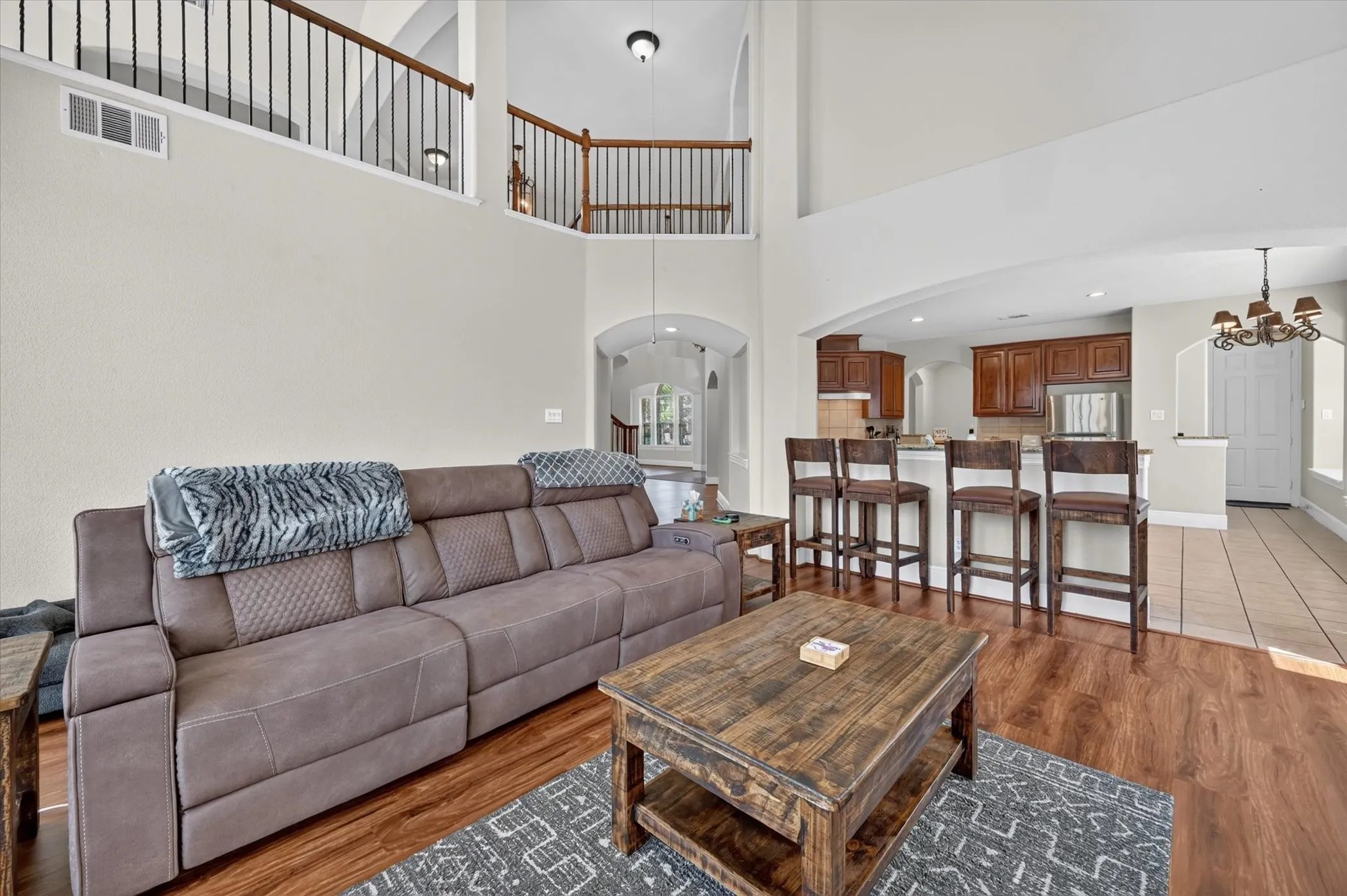 Vaulted ceilings, wood-finish flooring, kitchen with built-in cabinetry, and a second-level open railing