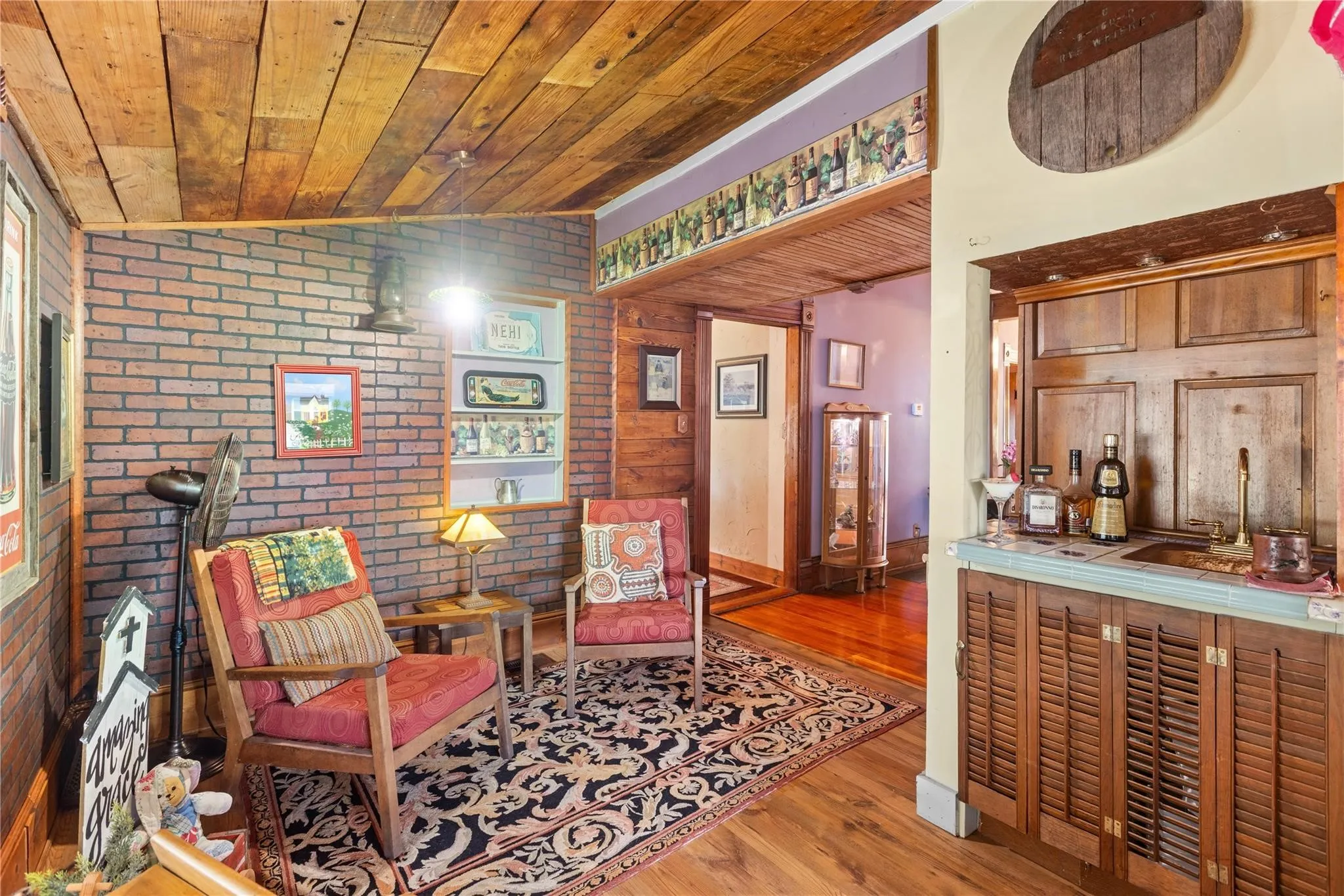Exposed brick wall, natural wood ceiling, wood-finish flooring, built-in wet bar with wood cabinetry, and recessed shelving