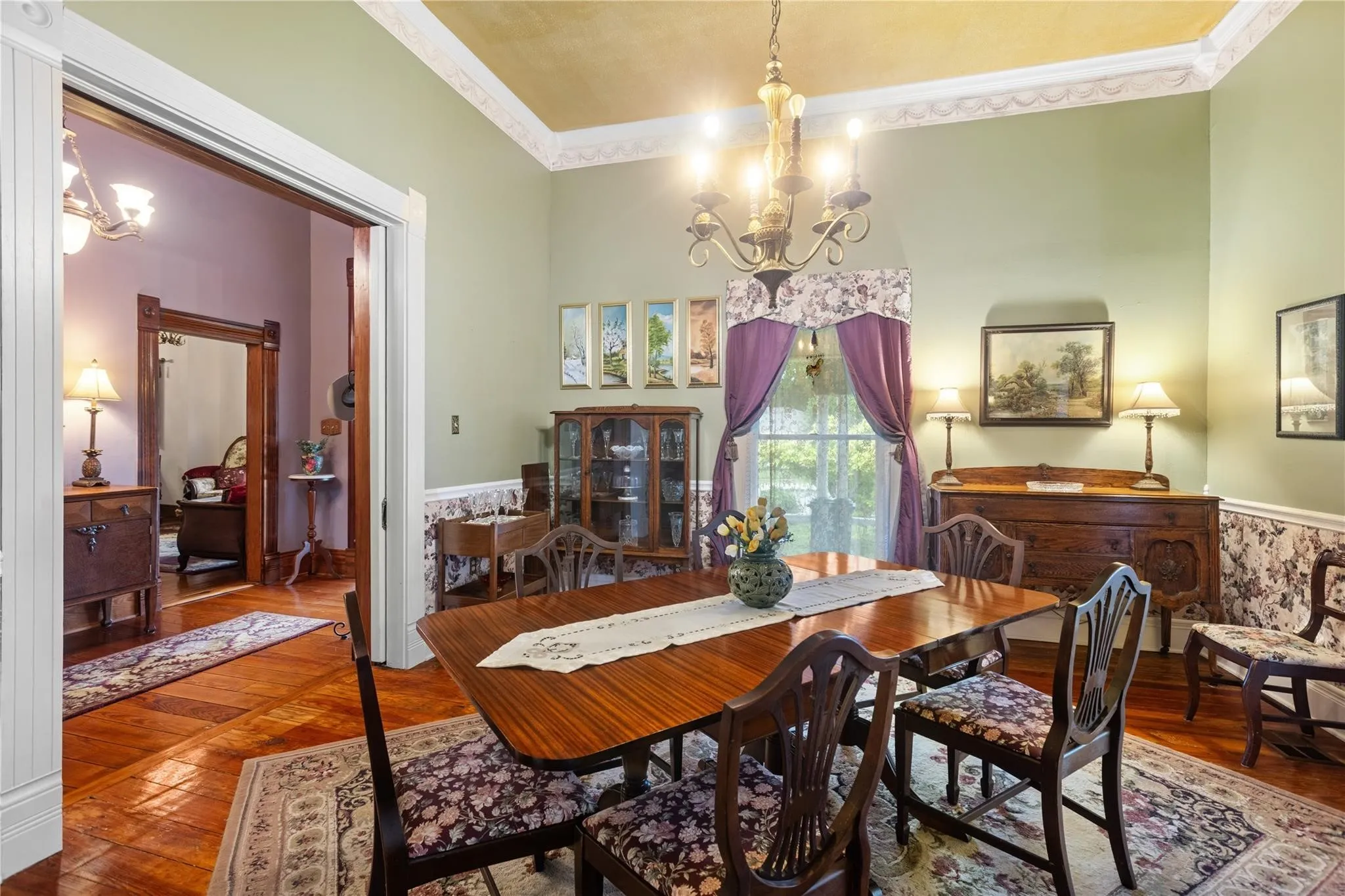 Formal dining area featuring rich wood-finish flooring, a decorative ceiling, and a prominent chandelier