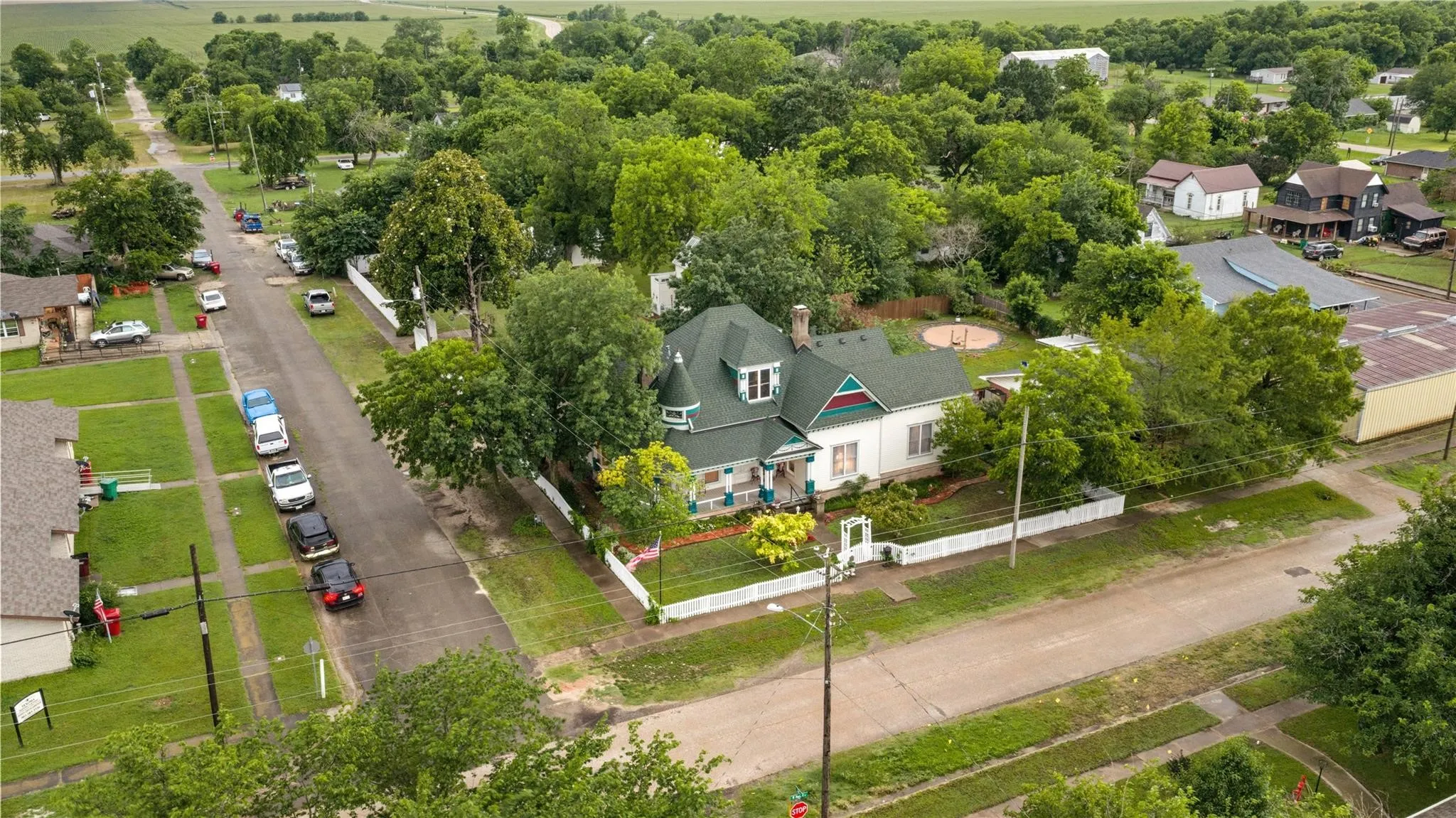 Property with an ornate turret, a green shingled roof, and a white picket fence