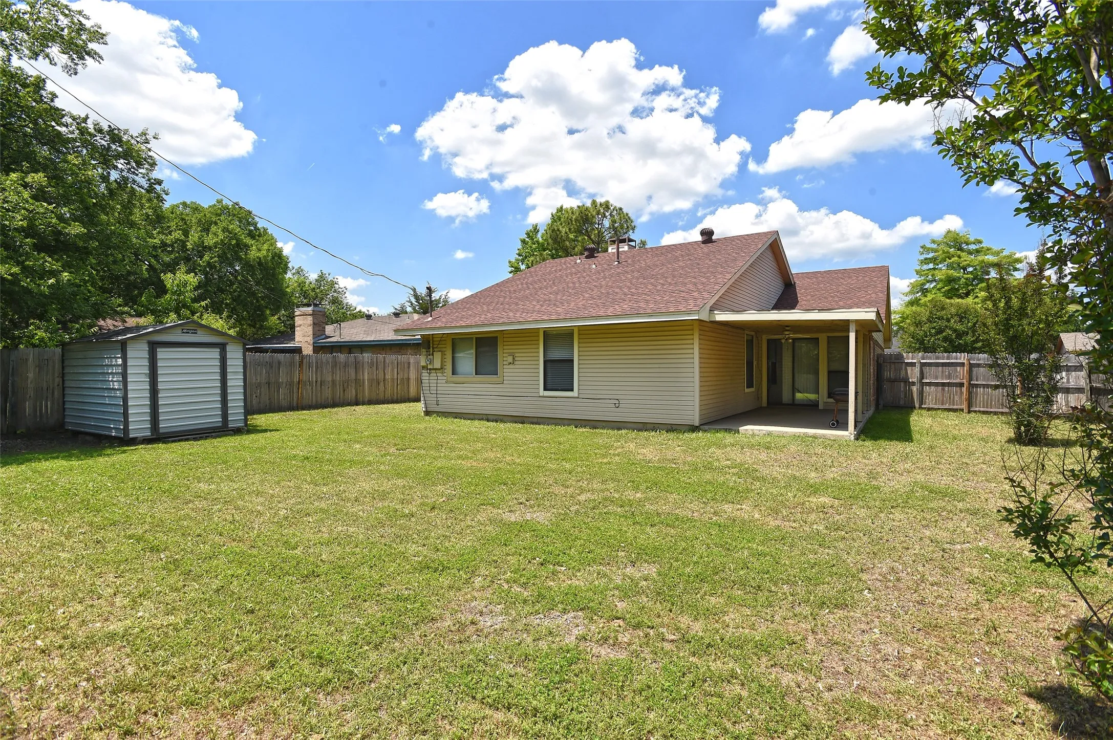 Large beautiful backyard with storage shed and covered back patio.