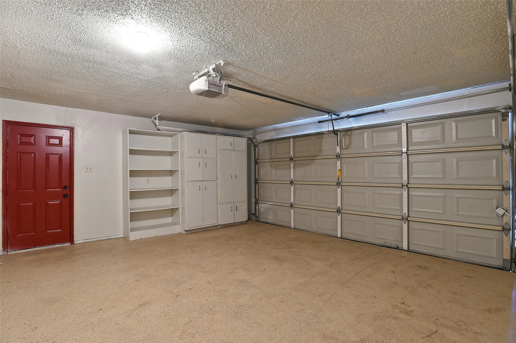 Large garage with built-in cabinets and shelving.