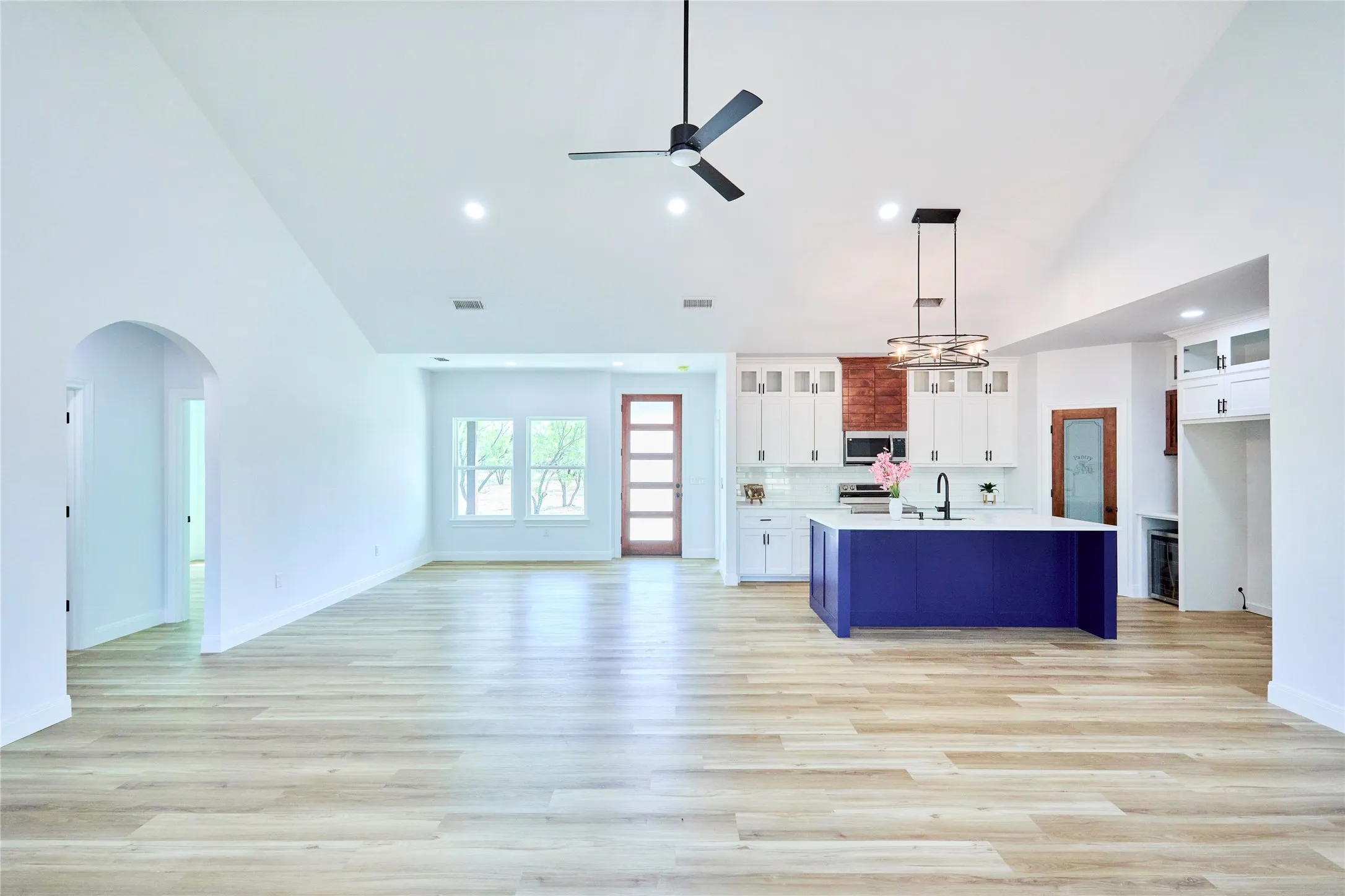 Vaulted ceilings with recessed lighting, wood-finish flooring, and arched doorways create an open atmosphere