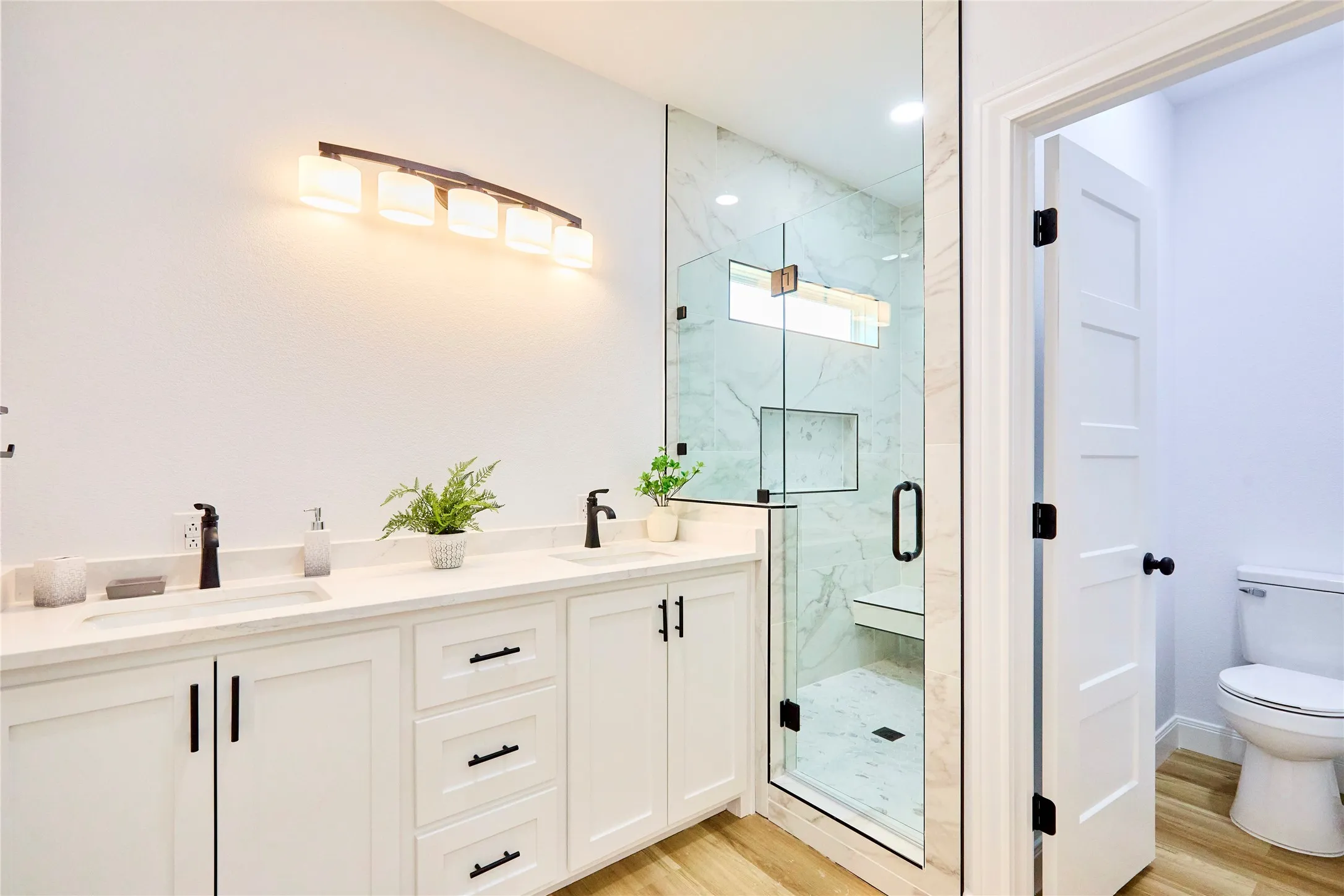 Dual vanity with undermount sinks, white cabinetry, and dark hardware