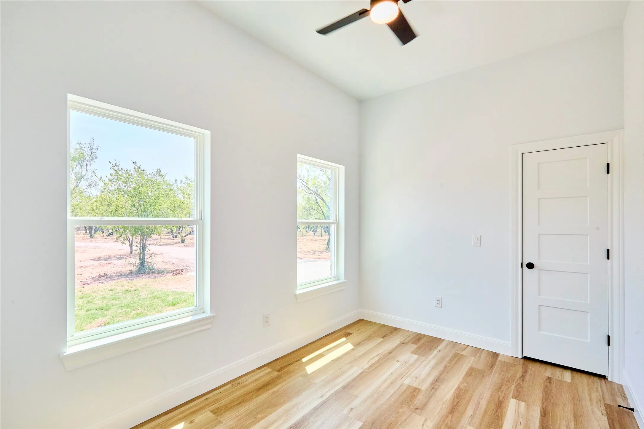 Vaulted ceilings, wood-finish flooring, two windows, and a ceiling fan