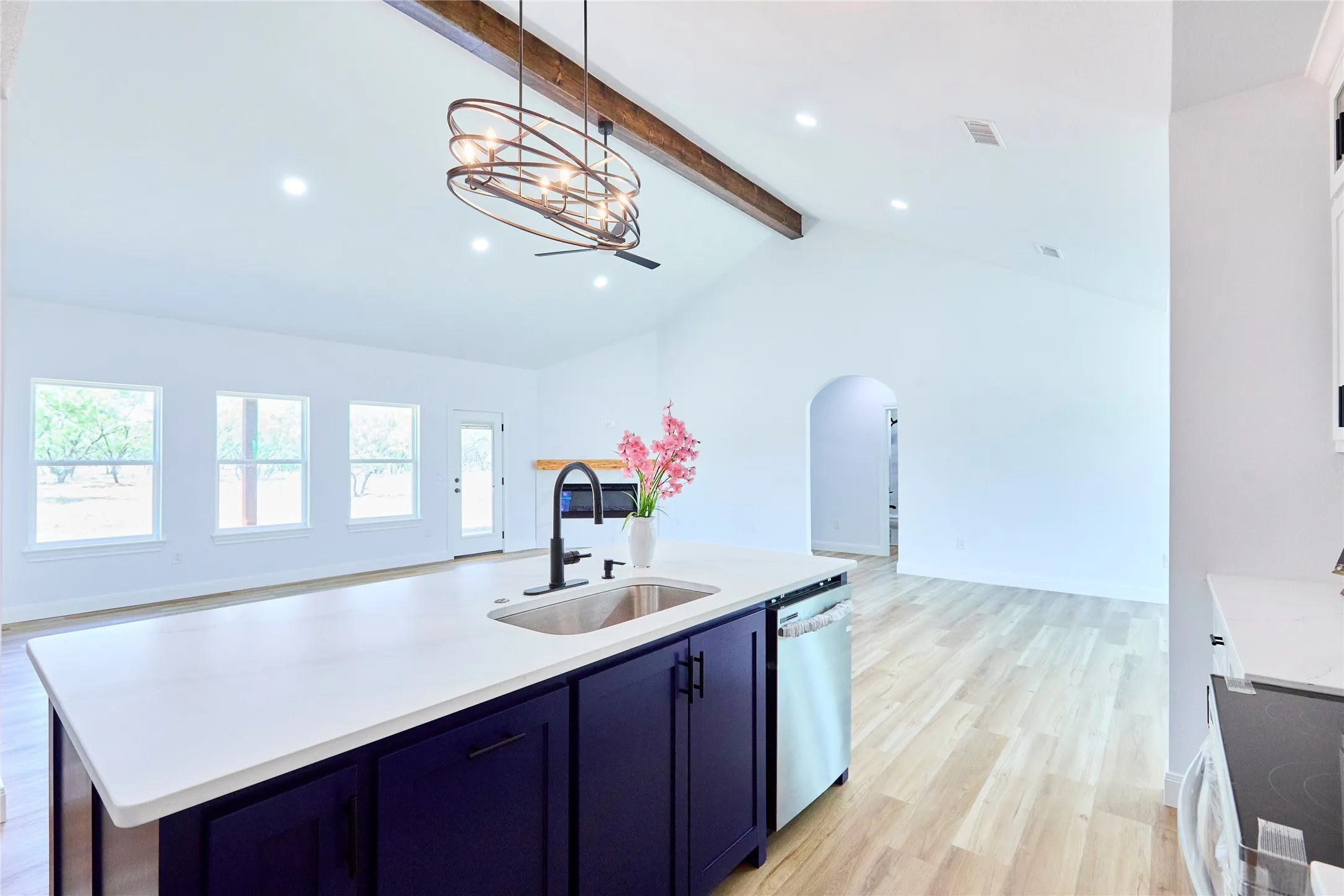 Vaulted ceiling with exposed wood beam, recessed lighting, and a contemporary chandelier