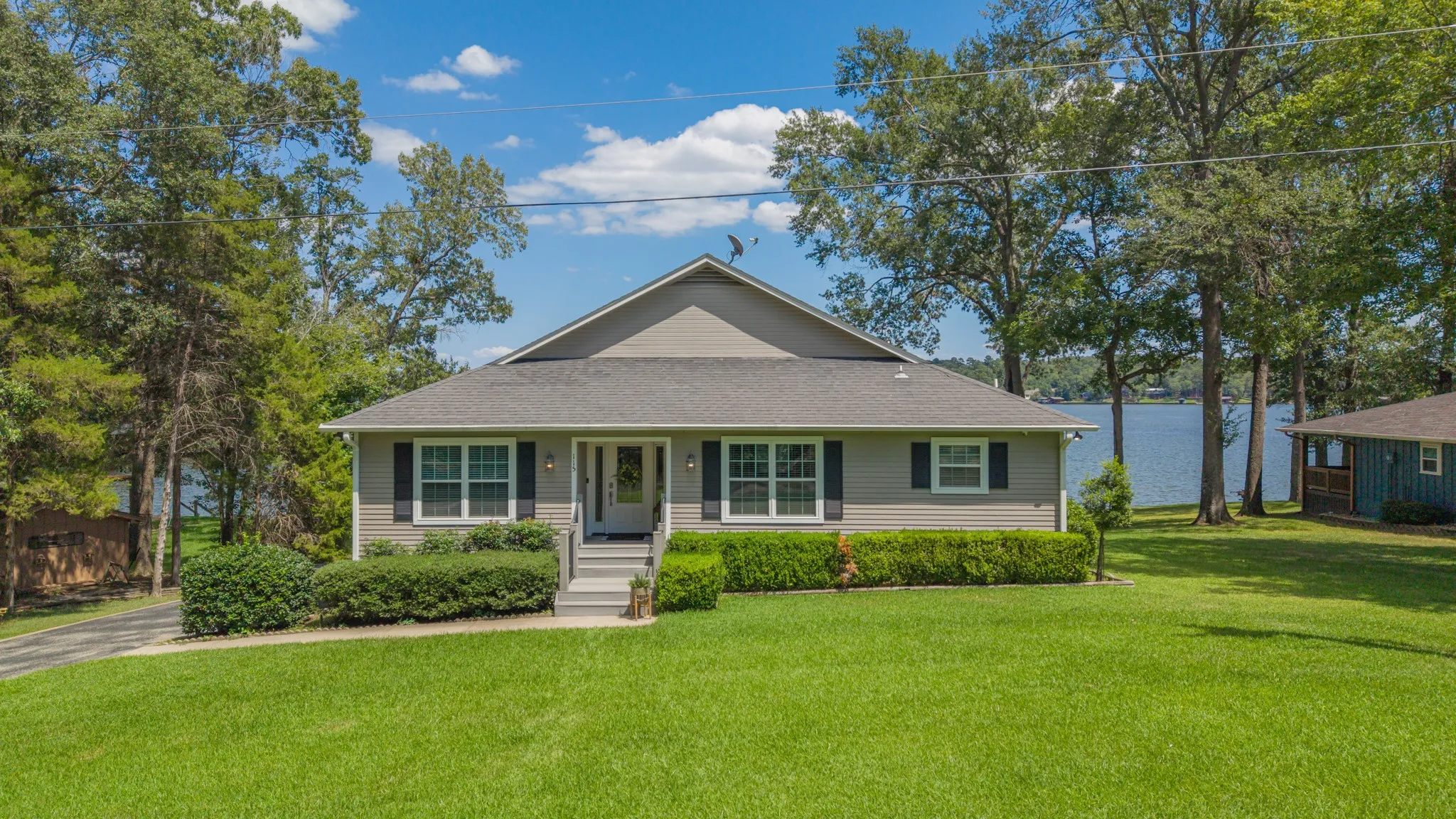 Ranch-style exterior with gray siding, white trim, and a dark shingle roof