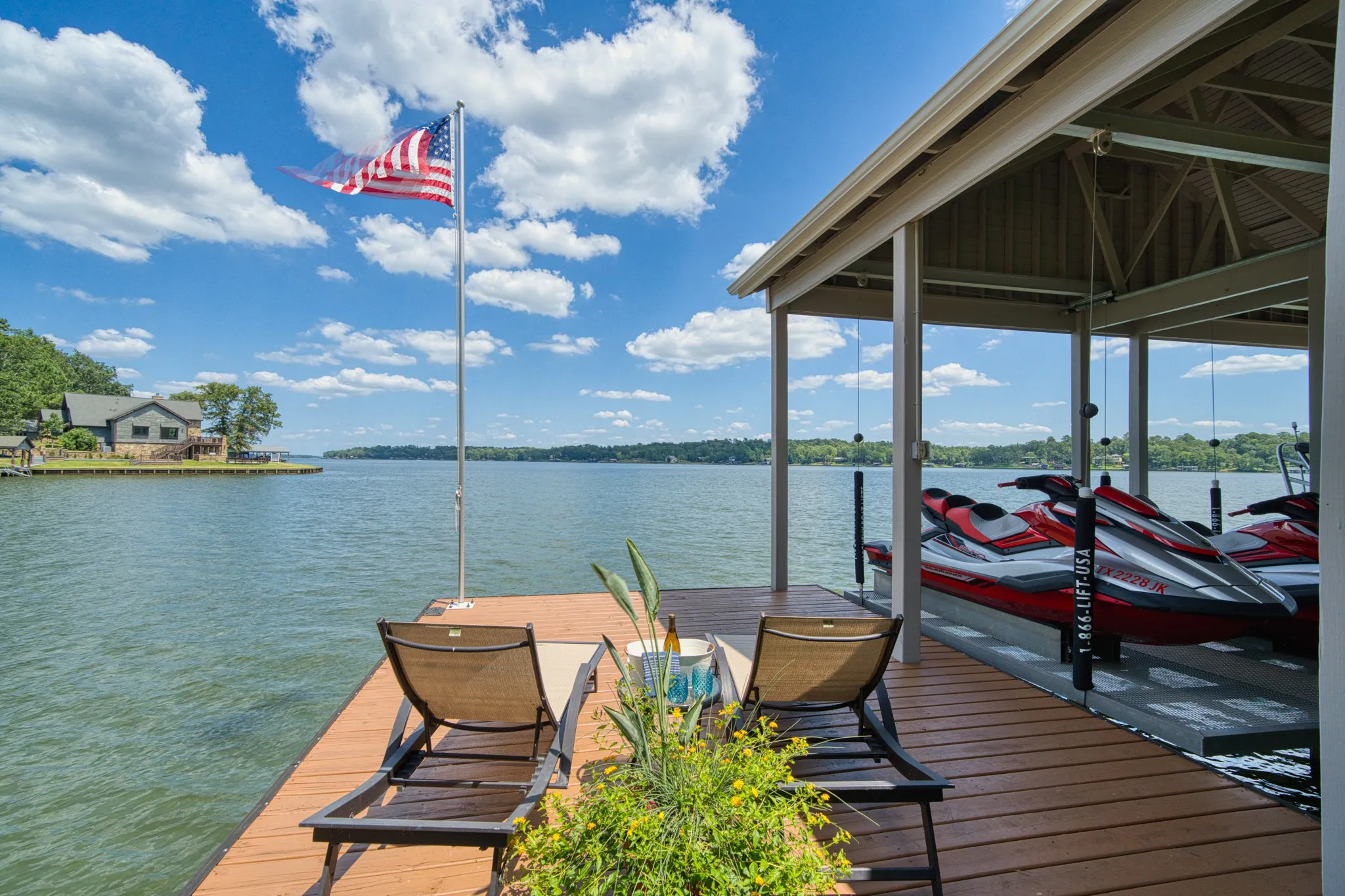 Expansive wood-finish dock with a covered boat slip, boat lift, and flagpole