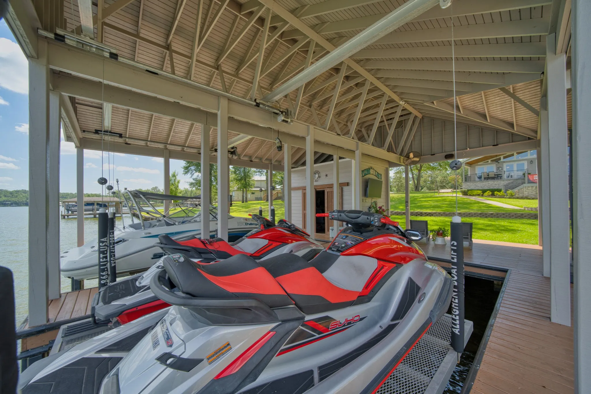 Covered boat dock featuring multiple boat slips, boat lifts, and a built-in storage room