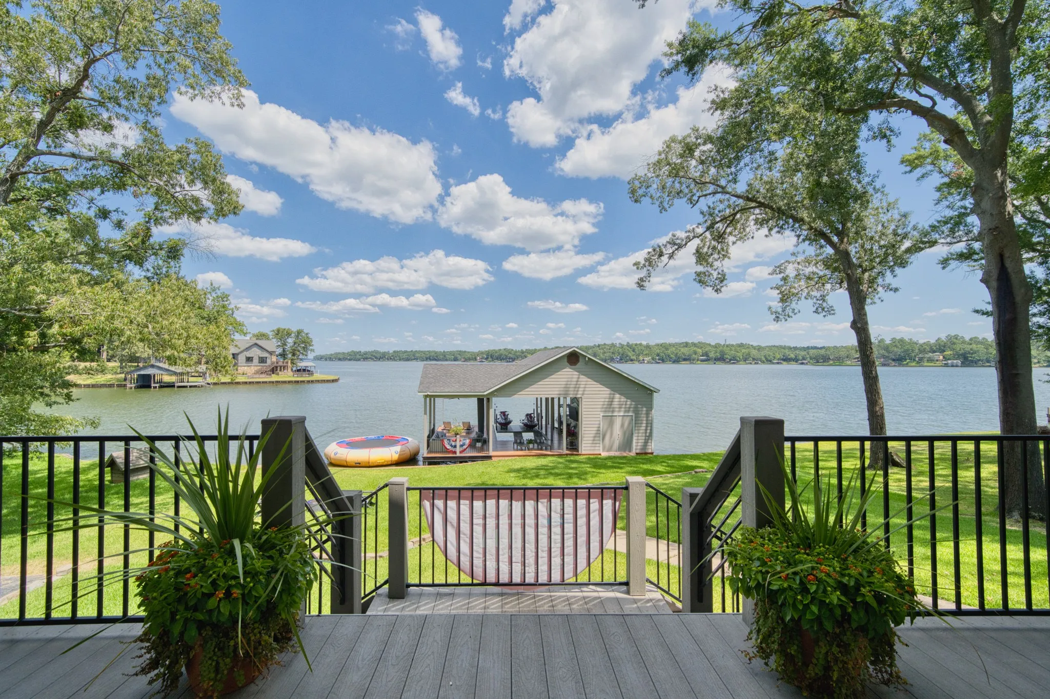 Lakefront property featuring a private boat house, expansive waterfront, and a spacious deck with dark railing
