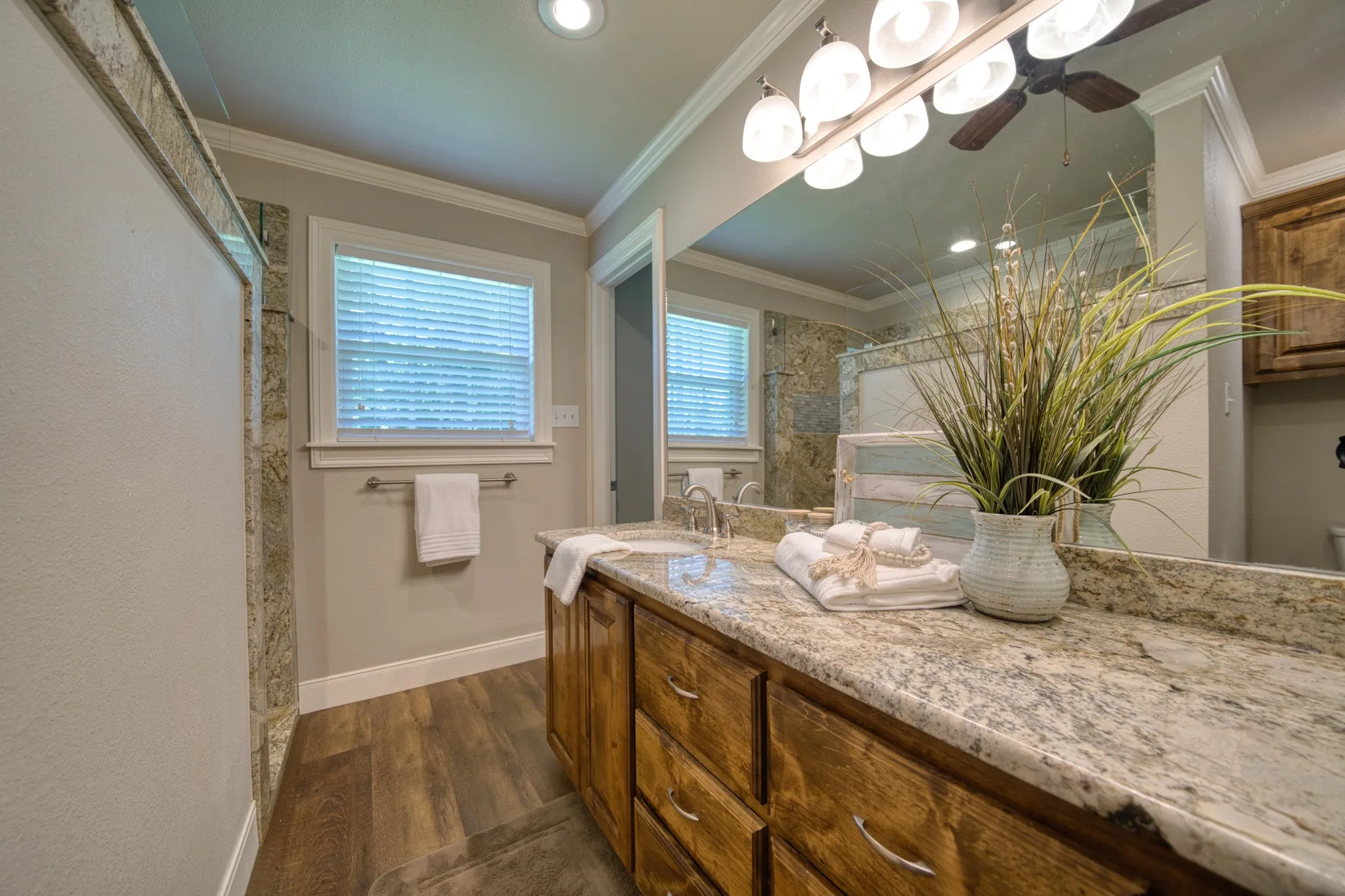 Wood-finish flooring, built-in vanity with wood cabinetry, light-toned countertop, and recessed lighting