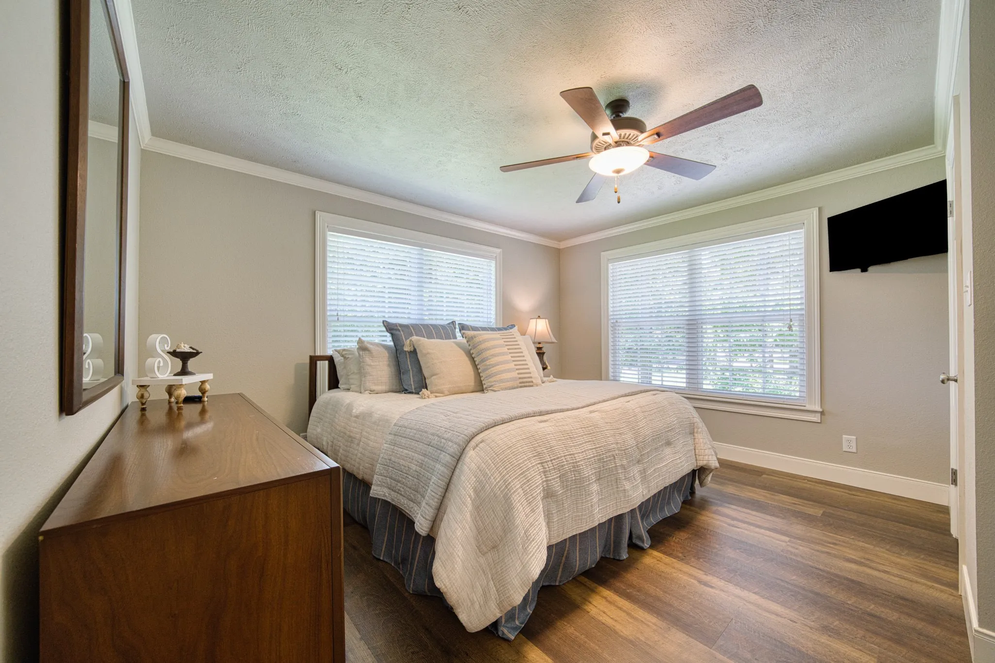 Wood-finish flooring, crown molding, and two windows with blinds