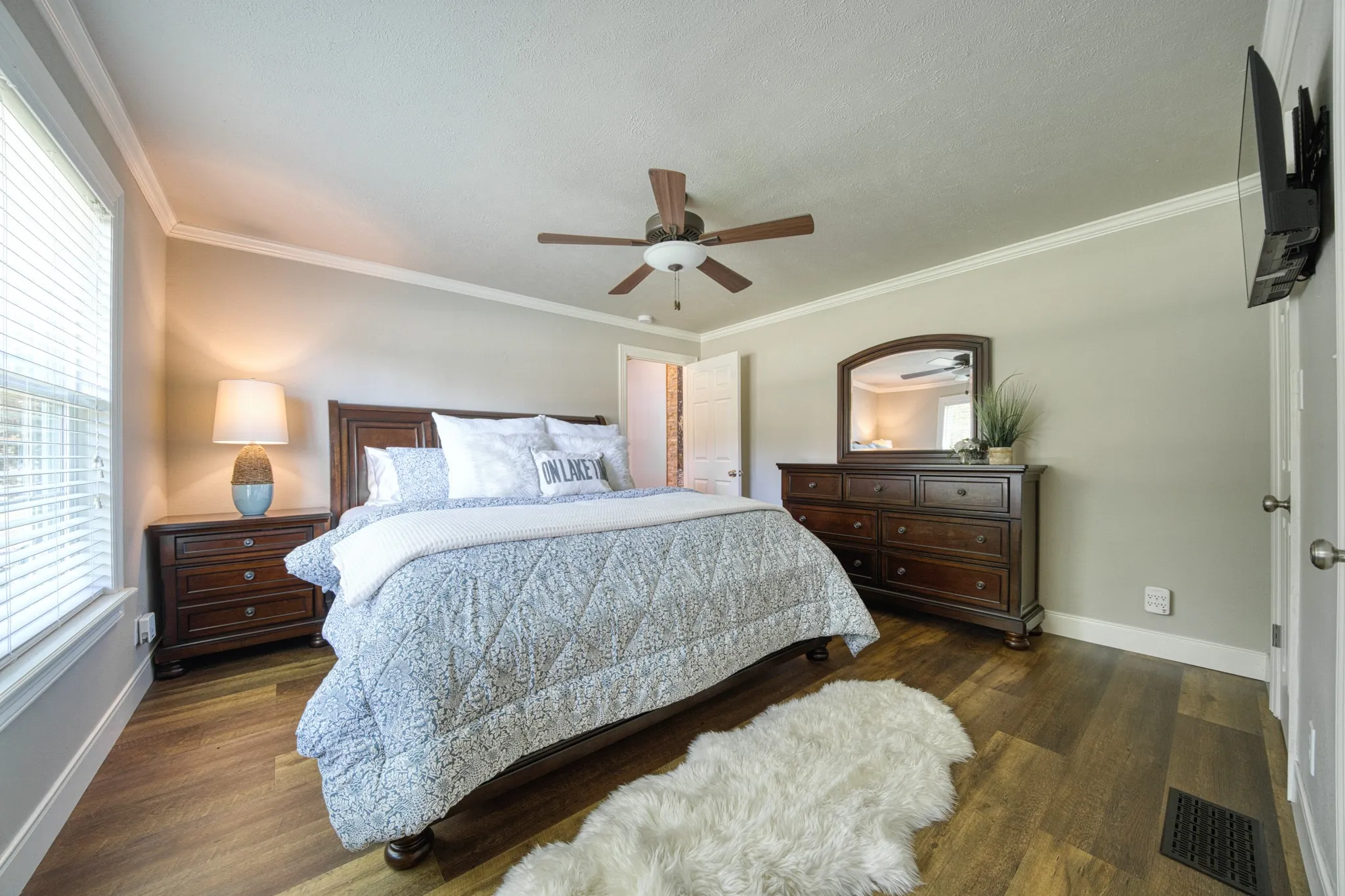 Wood-finish flooring, crown molding, and a ceiling fan with integrated lighting