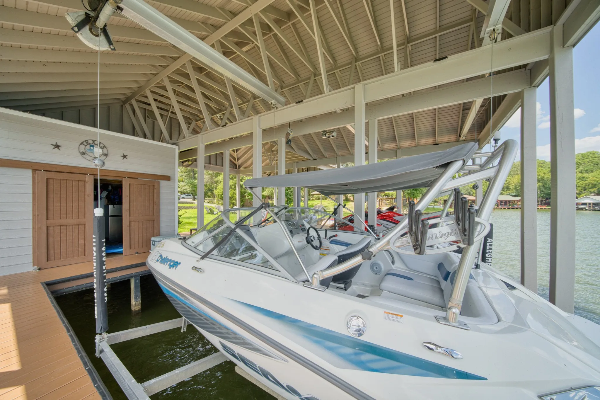 Covered boat dock featuring a boat lift, built-in storage, and composite decking
