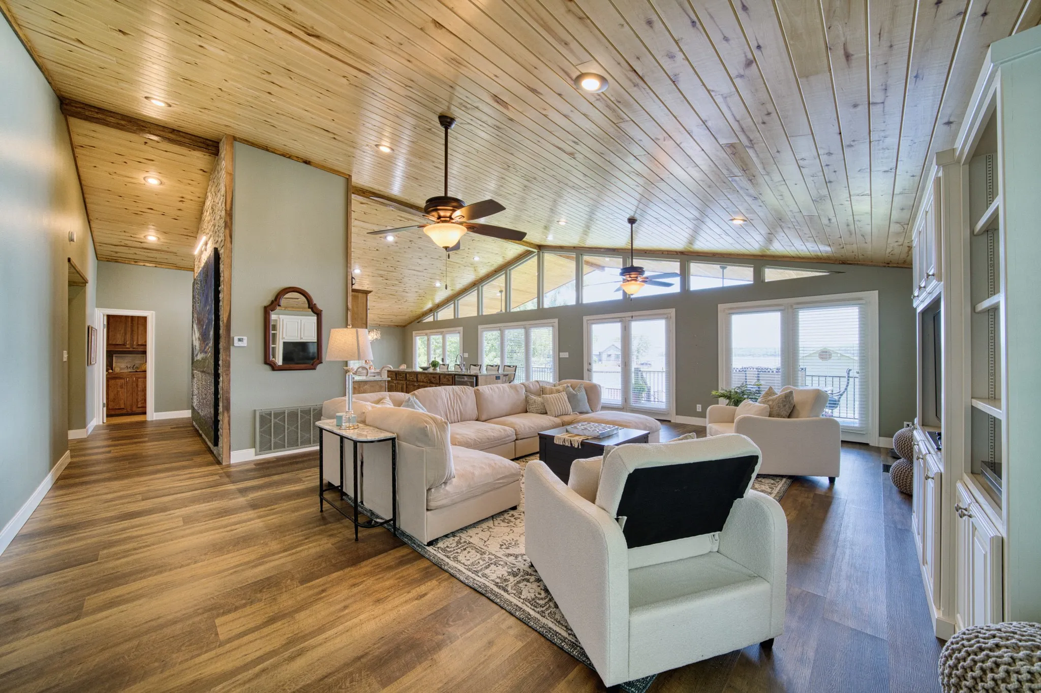 Expansive living area with wood-finish flooring, a vaulted wood-paneled ceiling, and recessed lighting