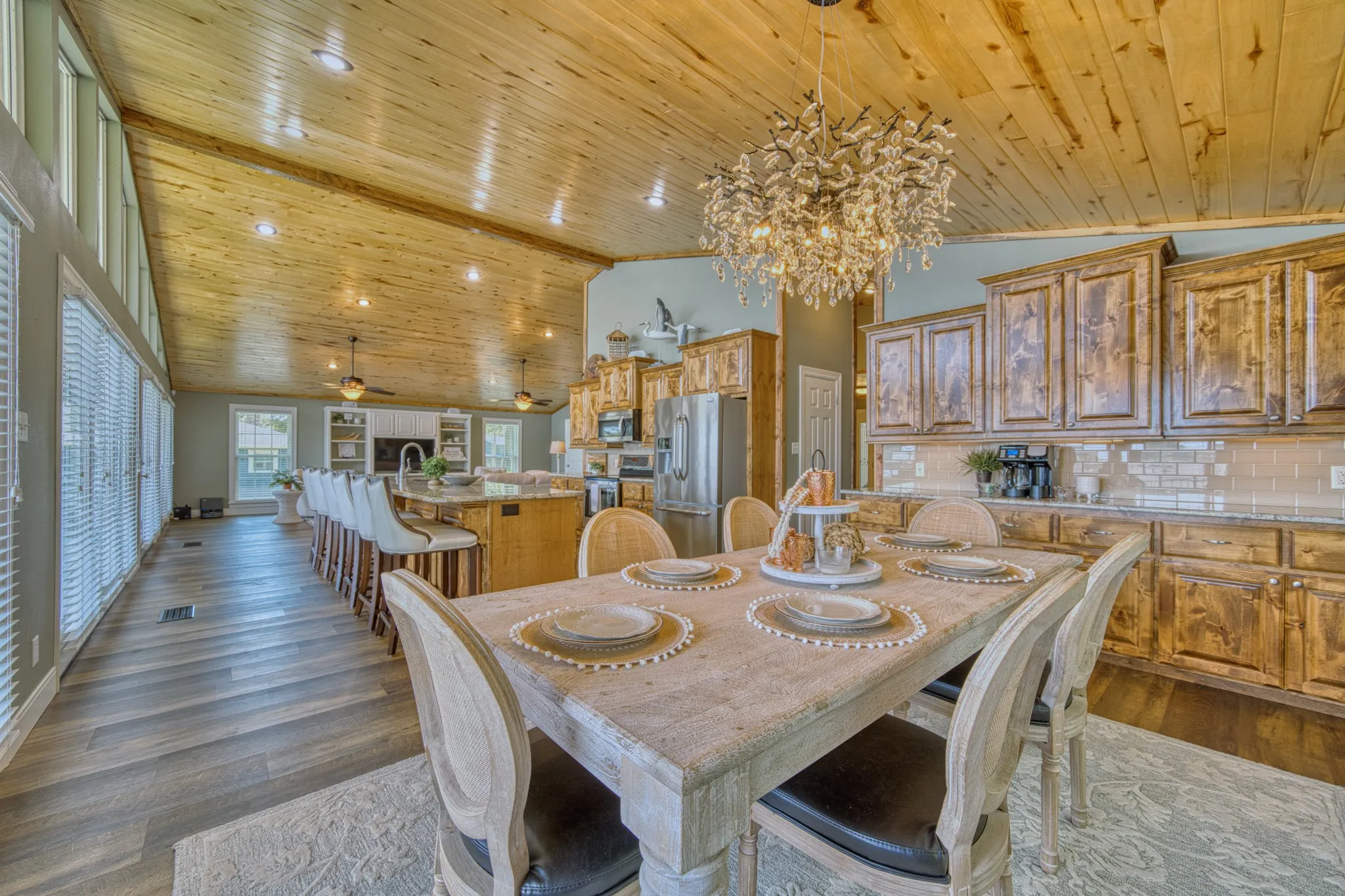 Vaulted wood-finish ceiling, wood-finish flooring, full-height windows, kitchen island with seating, and custom cabinetry