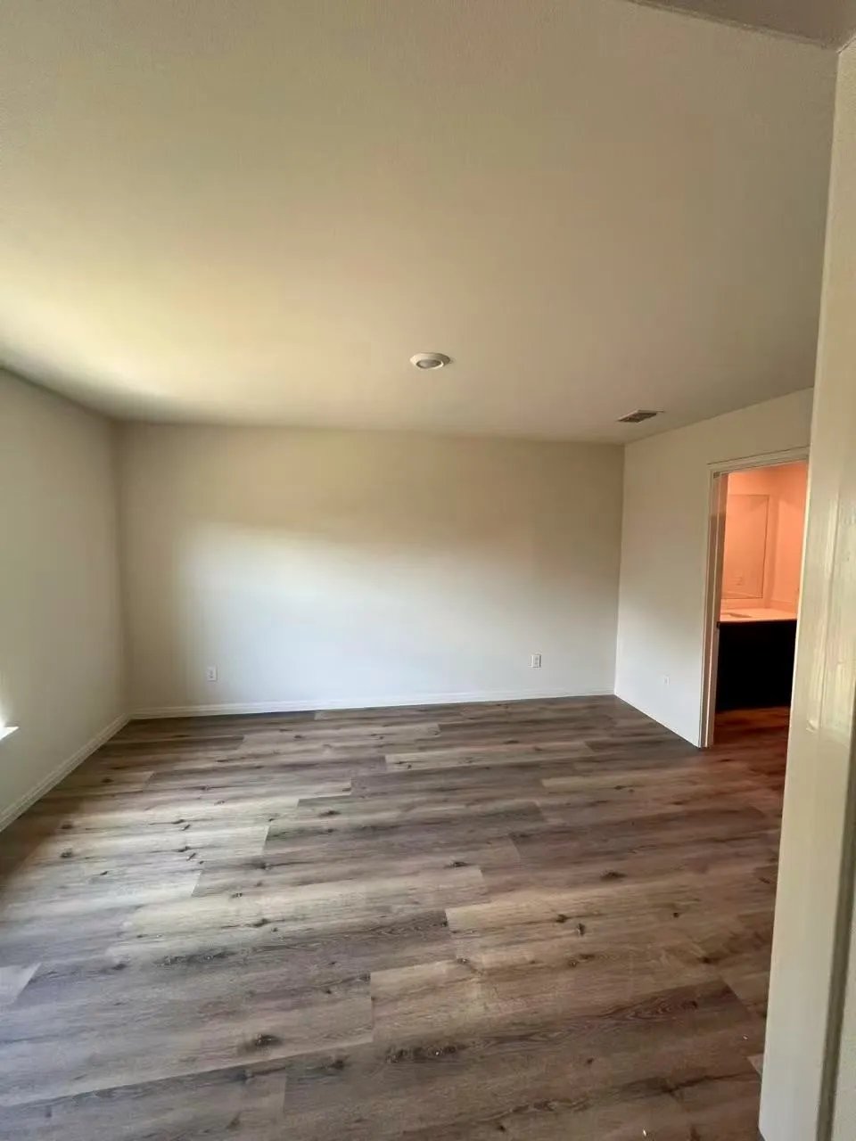 Spacious room featuring wood-finish flooring, recessed ceiling lighting, and neutral wall tones